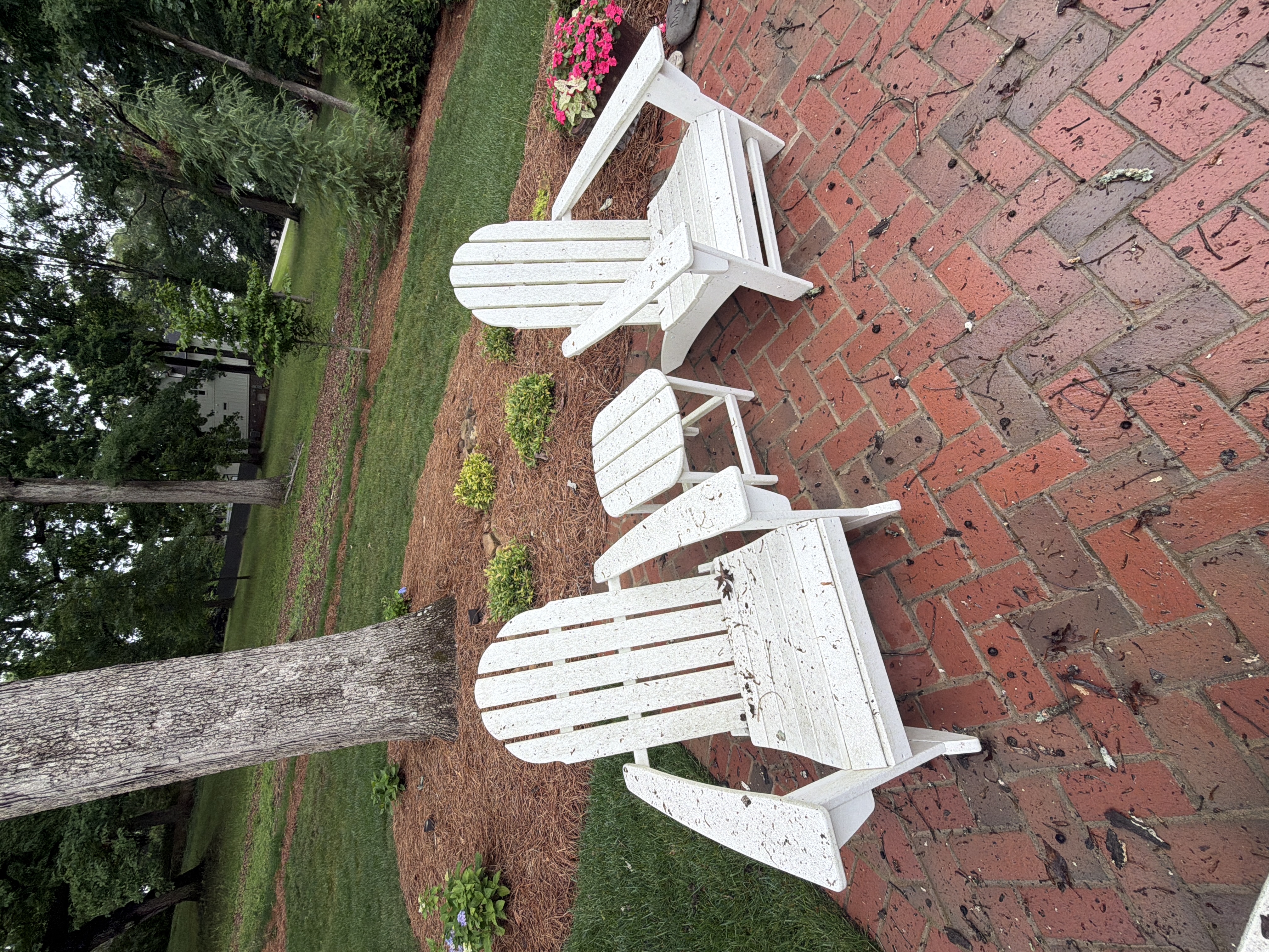 White Adirondack chairs on brick patio covered in leaf debris and grime before cleaning in Marietta, GA