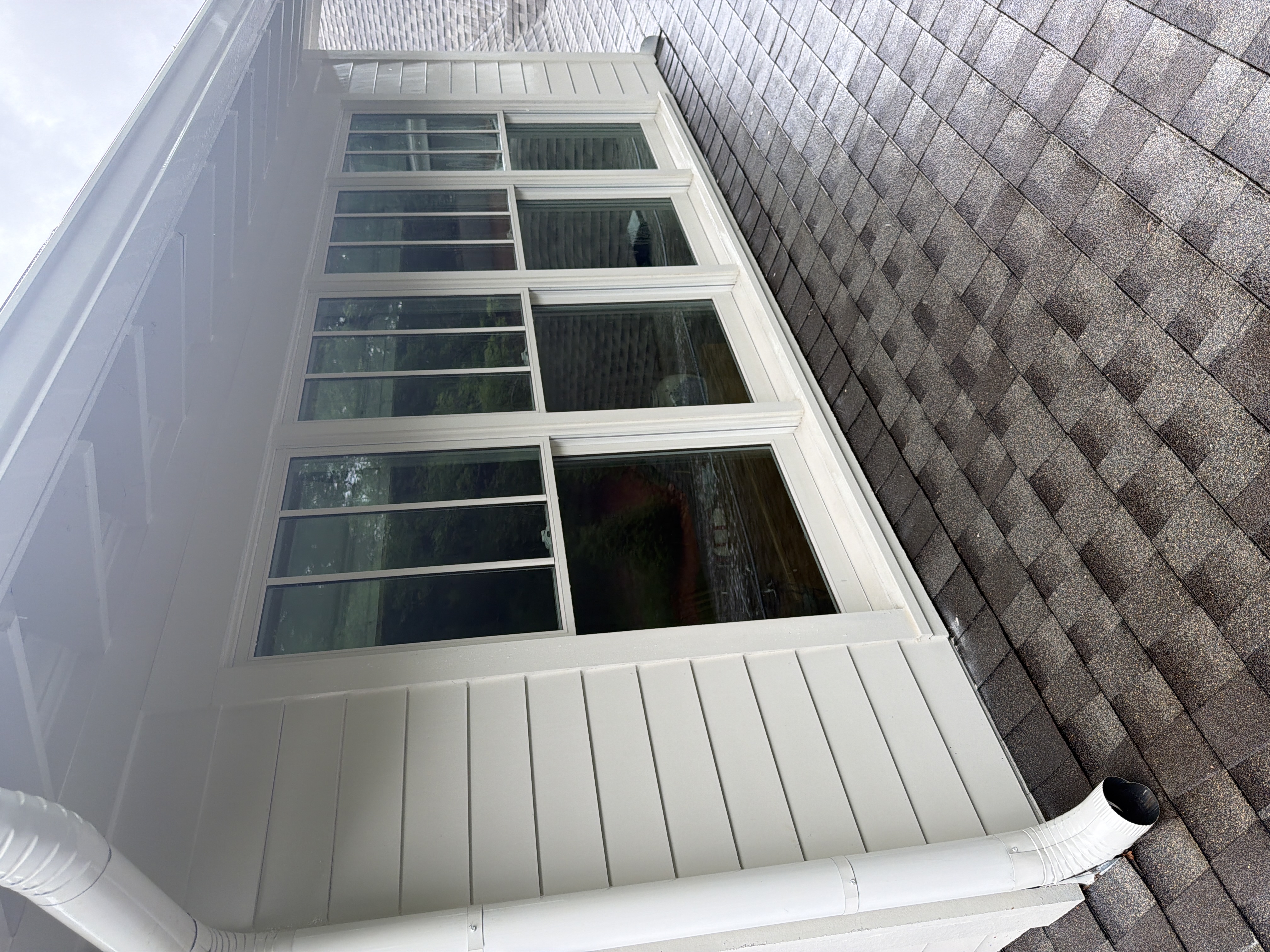 Clean white vinyl siding and large porch windows after house washing service on a Marietta, GA home