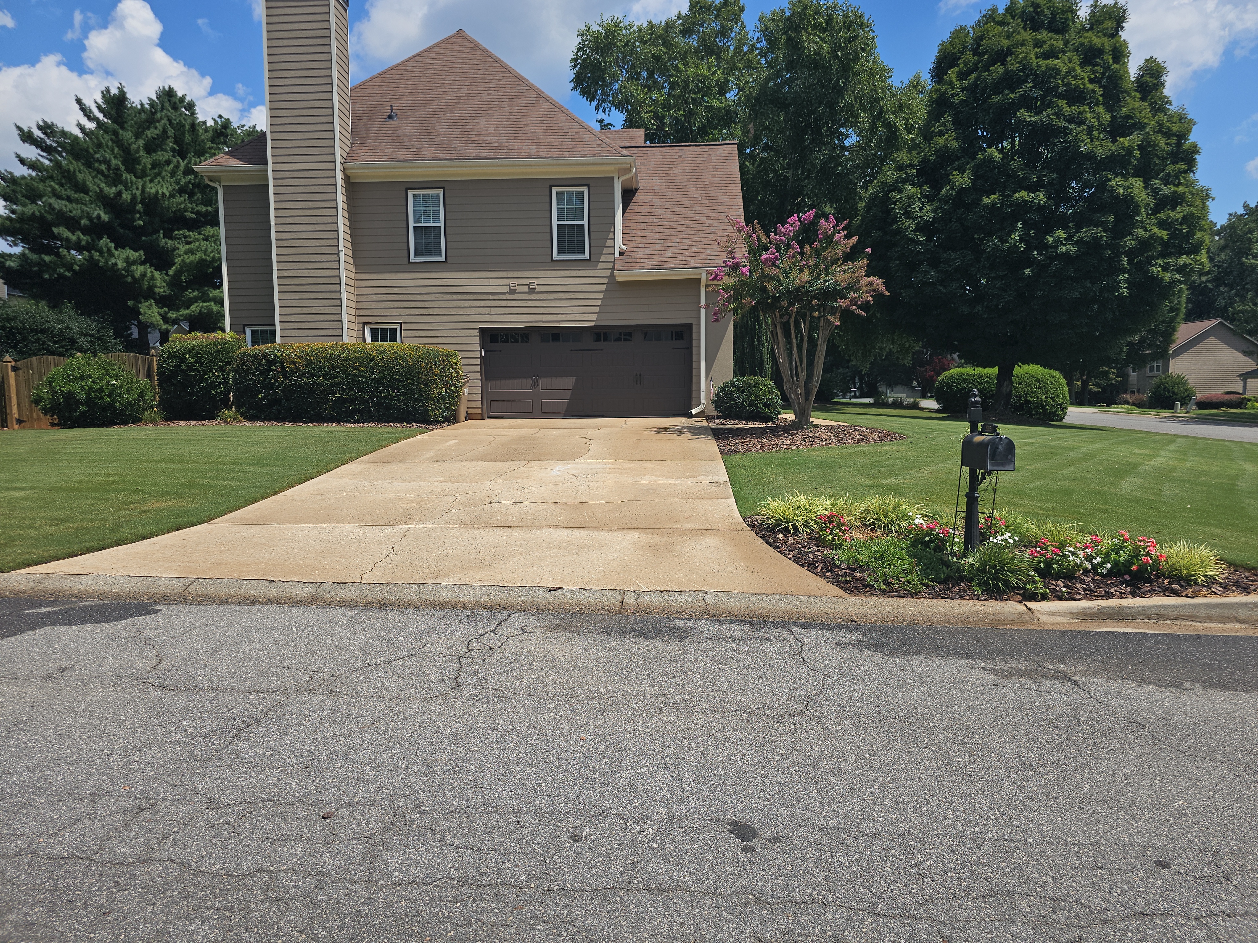 Concrete driveway at a residential home in Alpharetta, GA after pressure washing, viewed from the street with landscaping in foreground.
