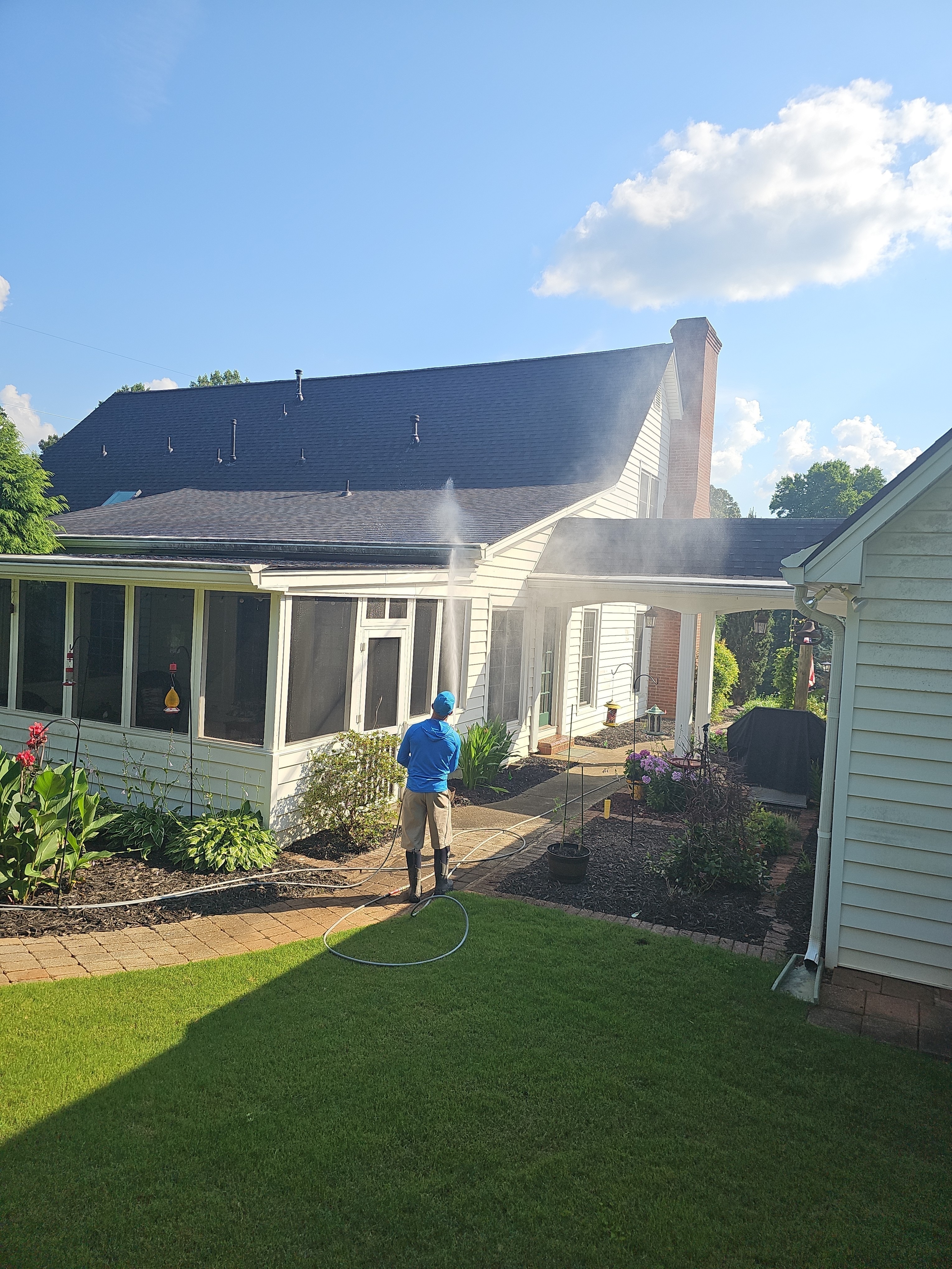 Technician spraying the exterior of a home with a pressure washer, mist visible in the air, at a house wash job in Kennesaw, GA.