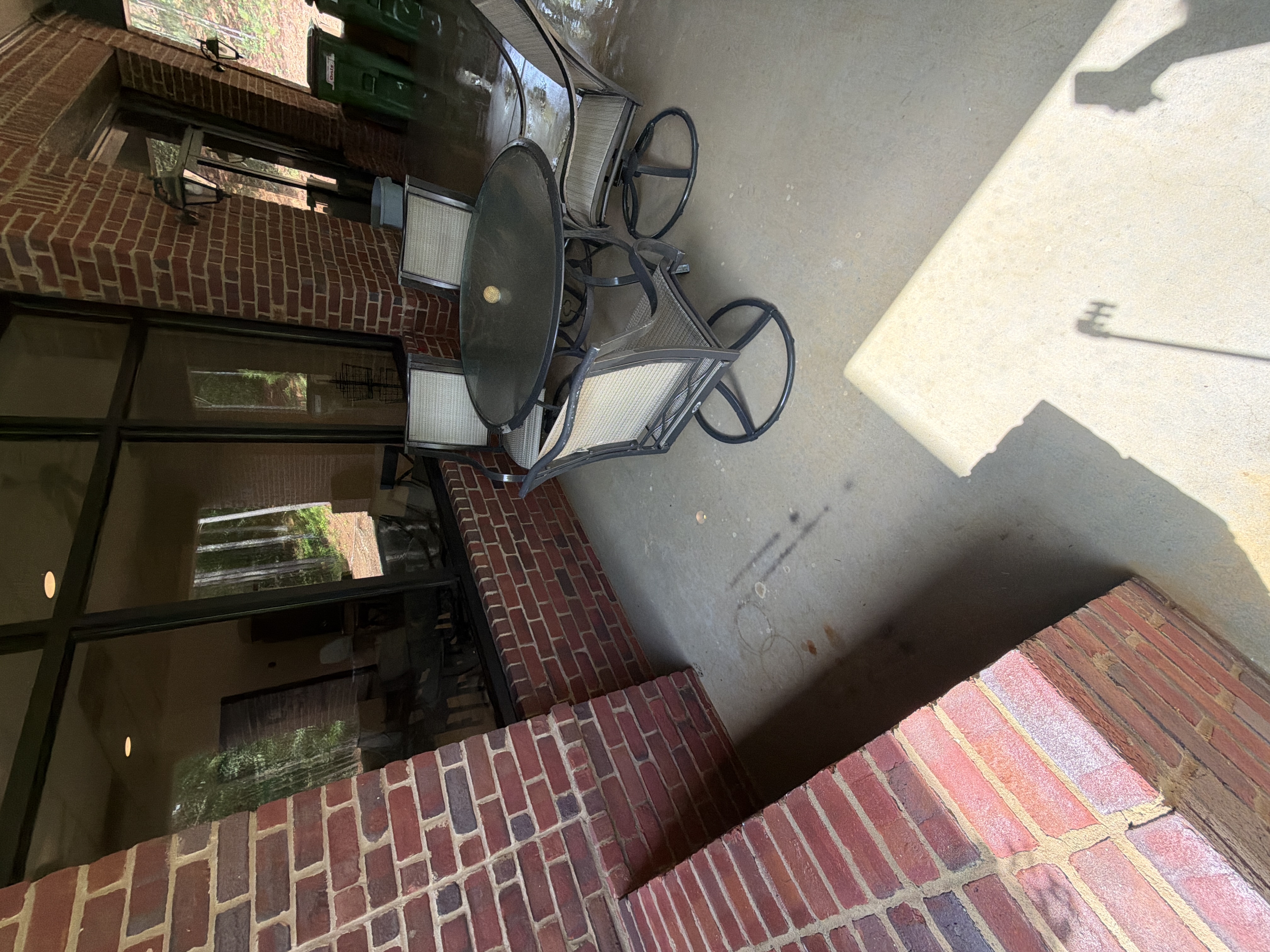 Covered concrete patio after pressure washing in Alpharetta, GA, showing clean floor with outdoor dining set and brick walls around an open-air space
