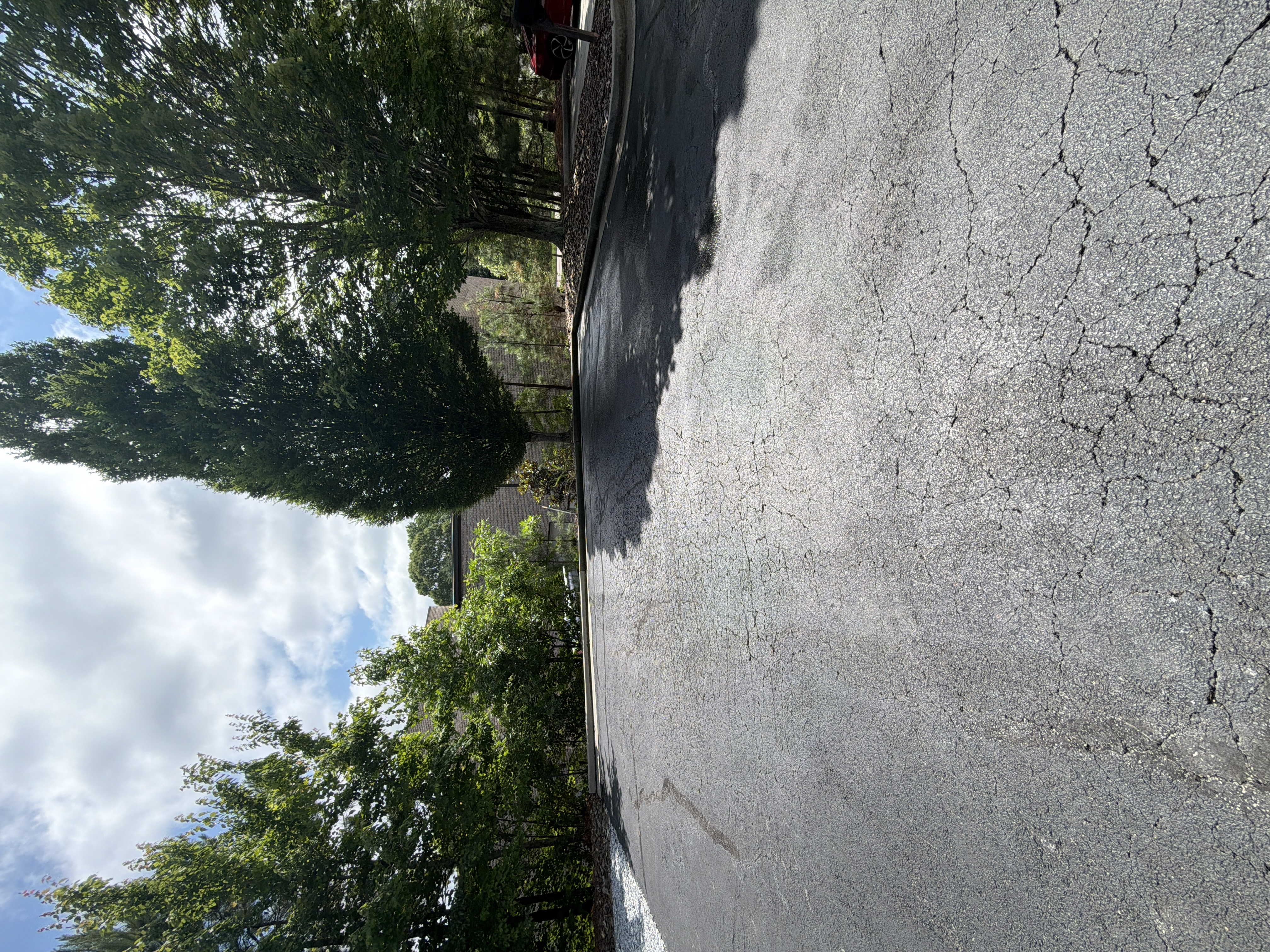 Commercial asphalt parking lot after pressure washing in Alpharetta, GA, showing clean dark pavement and clear access lane under bright partly cloudy sky