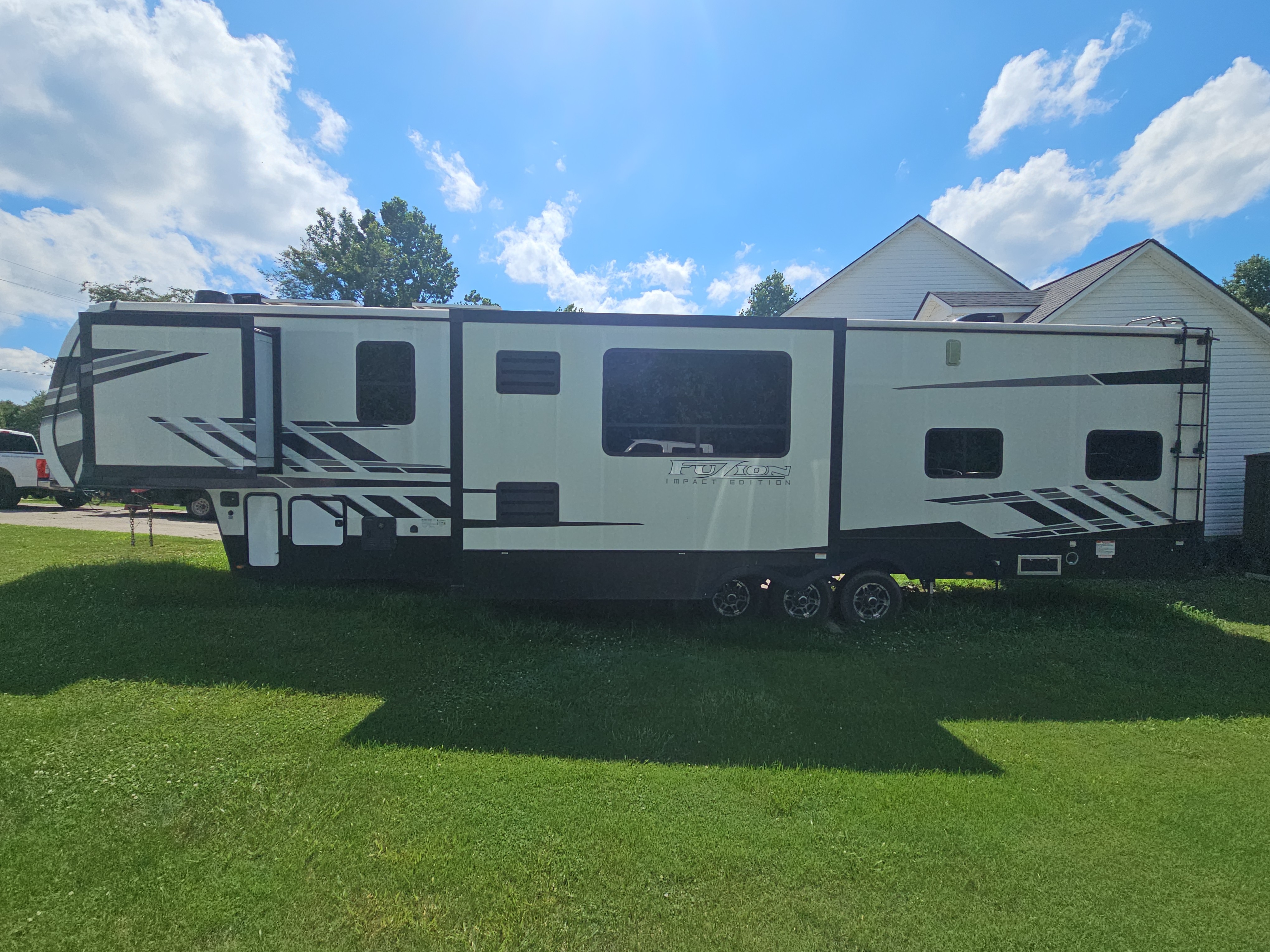 White Fuzion Impact Edition fifth-wheel RV parked on a grass lawn beside a residential home in Canton, GA.