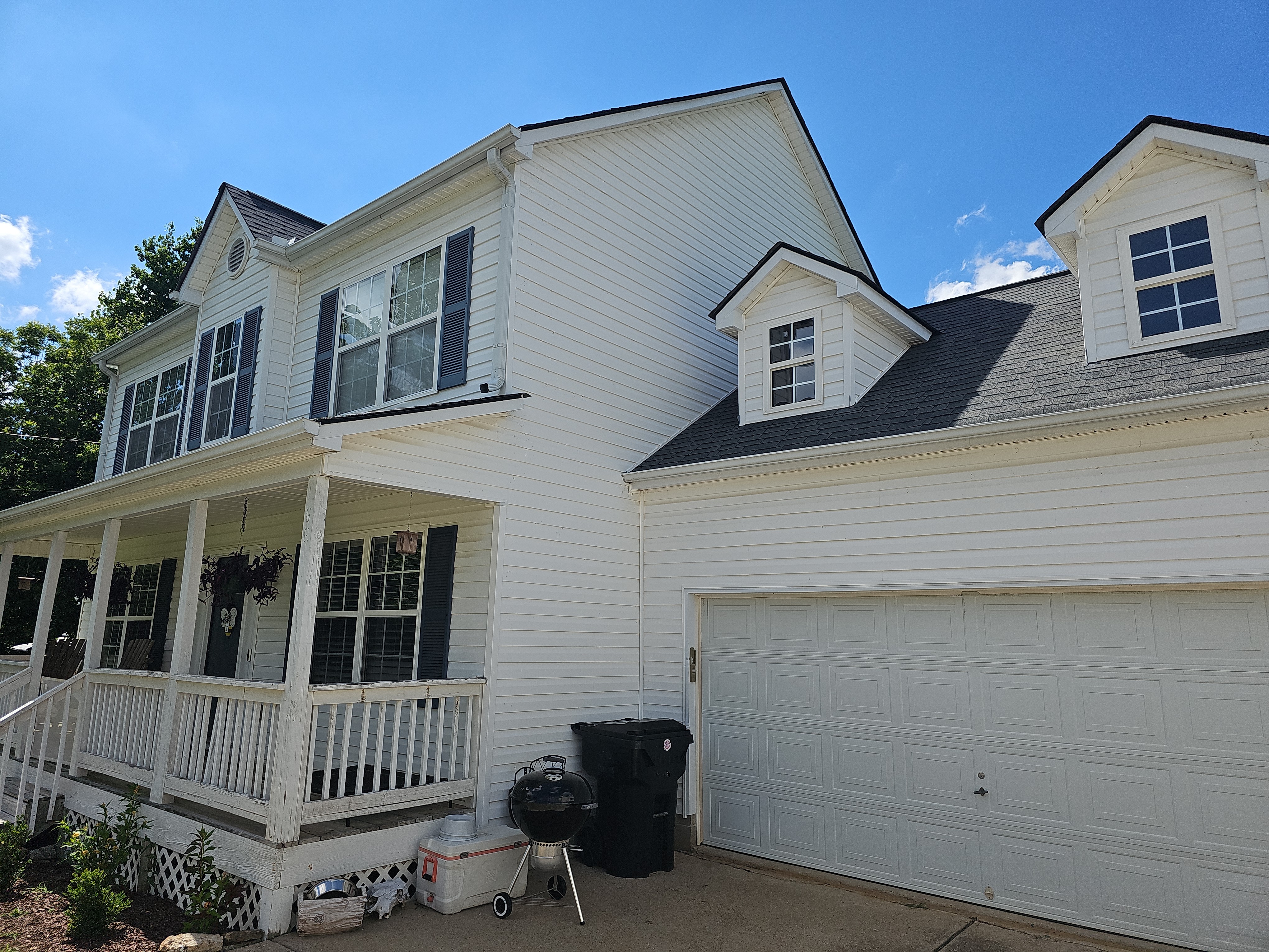 Side-angle view of a two-story home showing white vinyl siding, covered porch, and attached garage in Canton, GA.