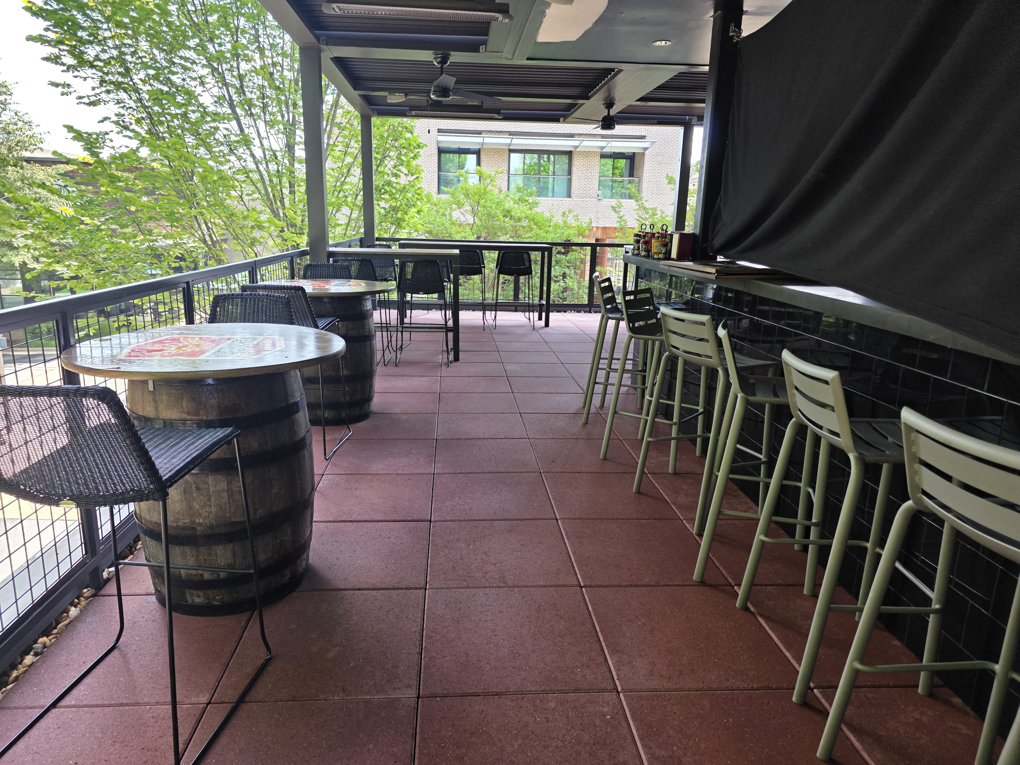 Wide view of a covered rooftop bar patio with red concrete tile flooring and barrel tables at a commercial degreasing job in Alpharetta, GA.