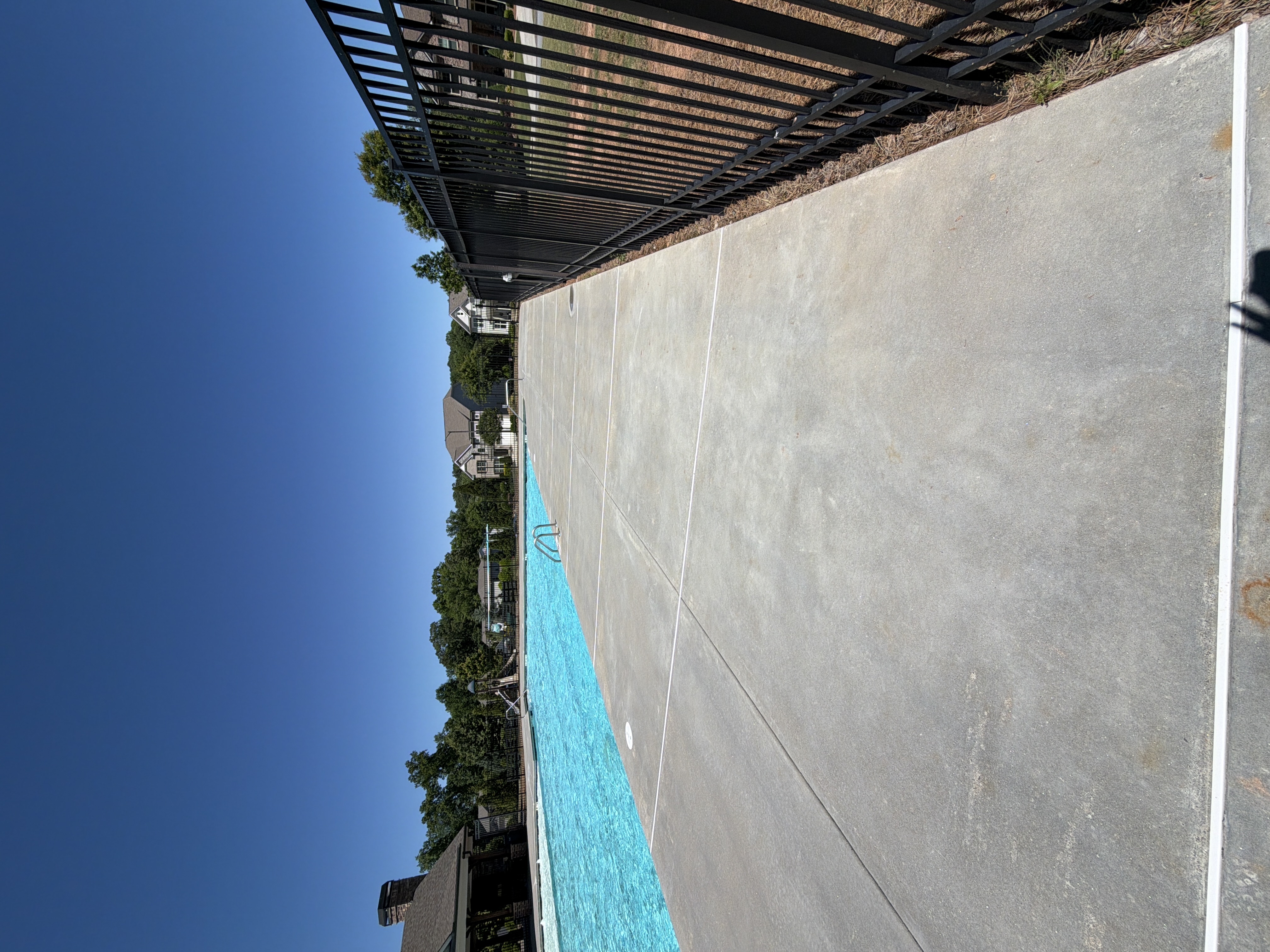 Long section of concrete pool deck pressure-washed beside community pool in Canton, GA, clean and even