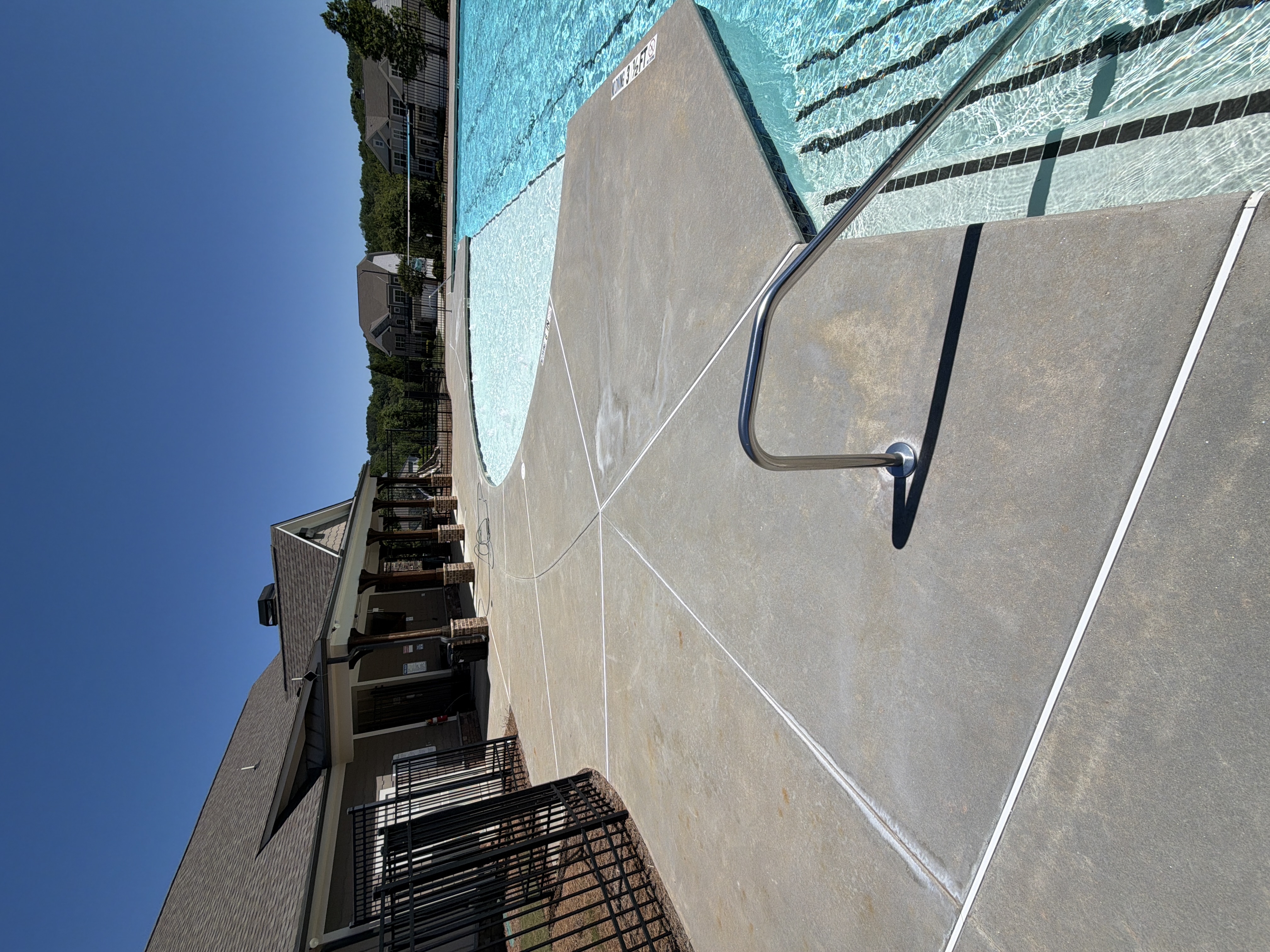 Wide-angle view of pressure-washed pool deck with pool ladder and clubhouse in background, Canton, GA