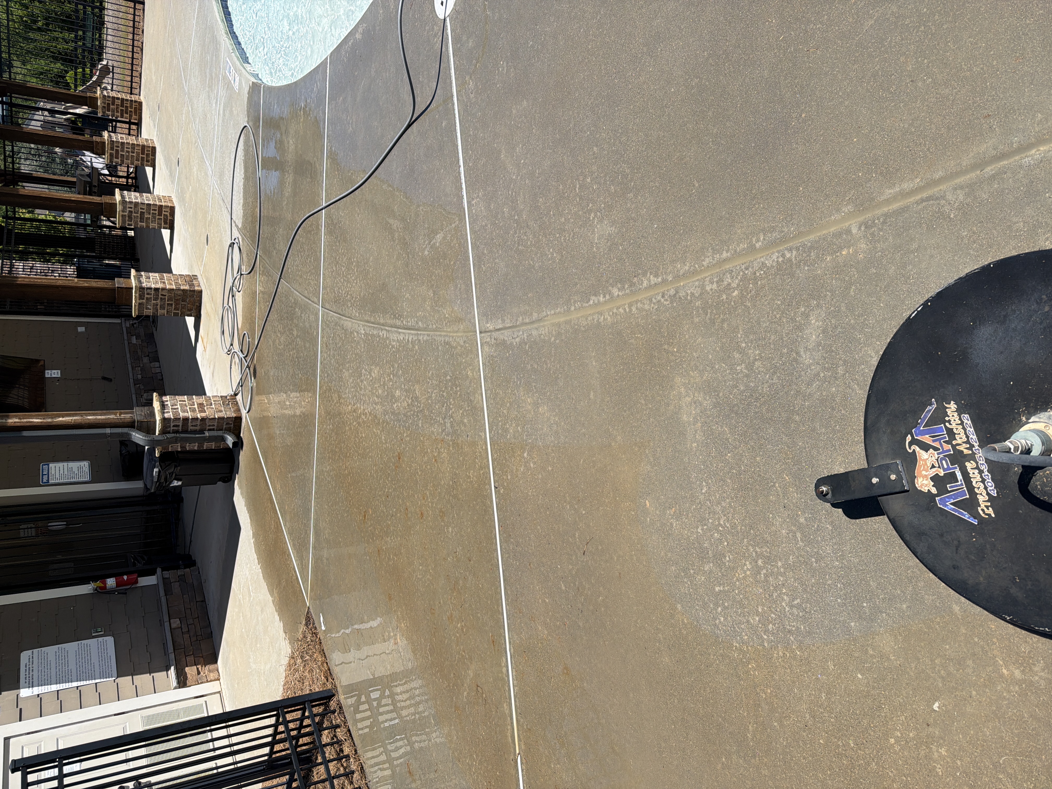 Surface cleaner in action on concrete pool deck mid-wash, showing before-and-after contrast in Canton, GA