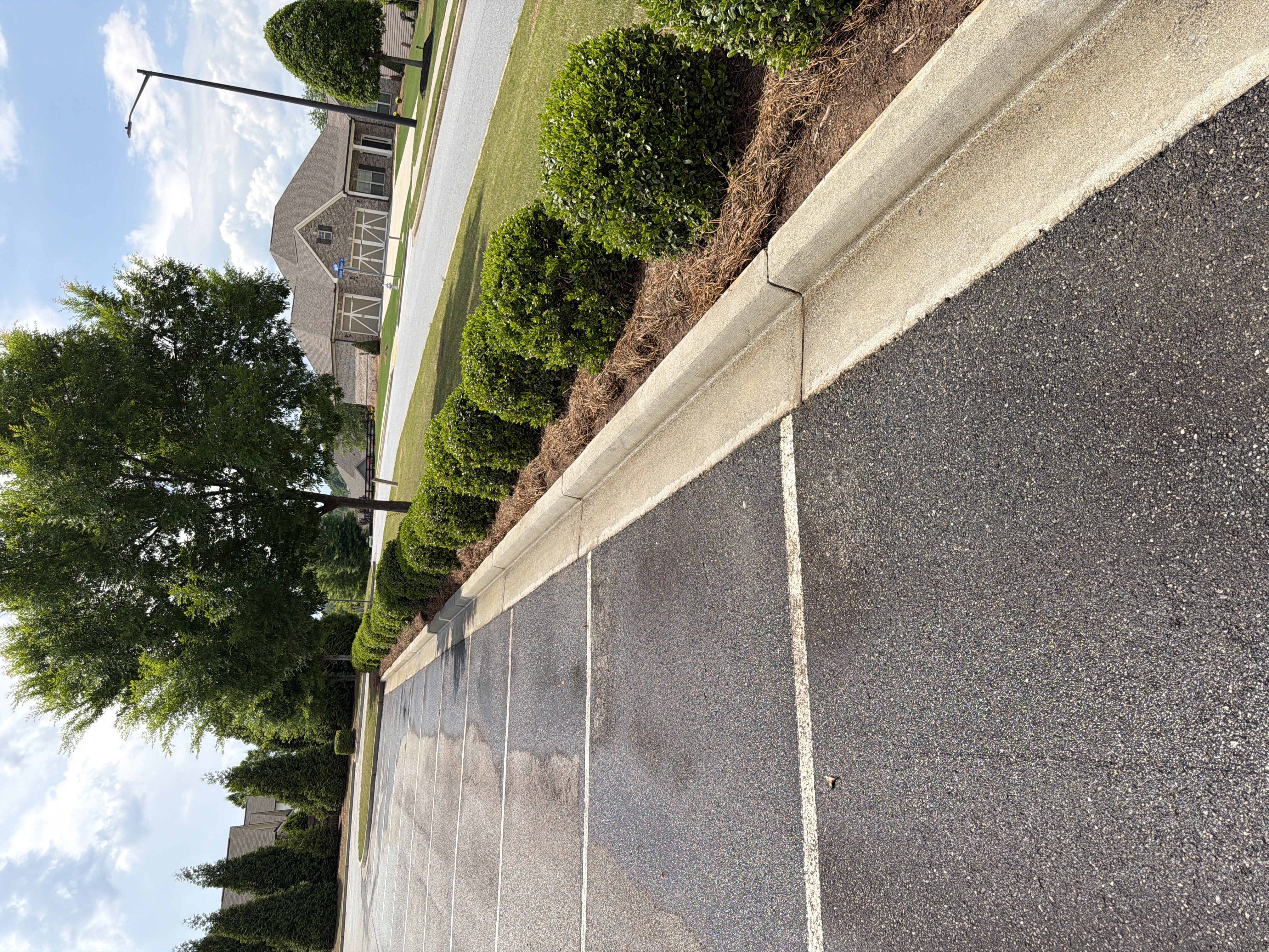 Clean concrete curb edging a commercial parking lot after pressure washing in Canton, GA, with bright white surface visible