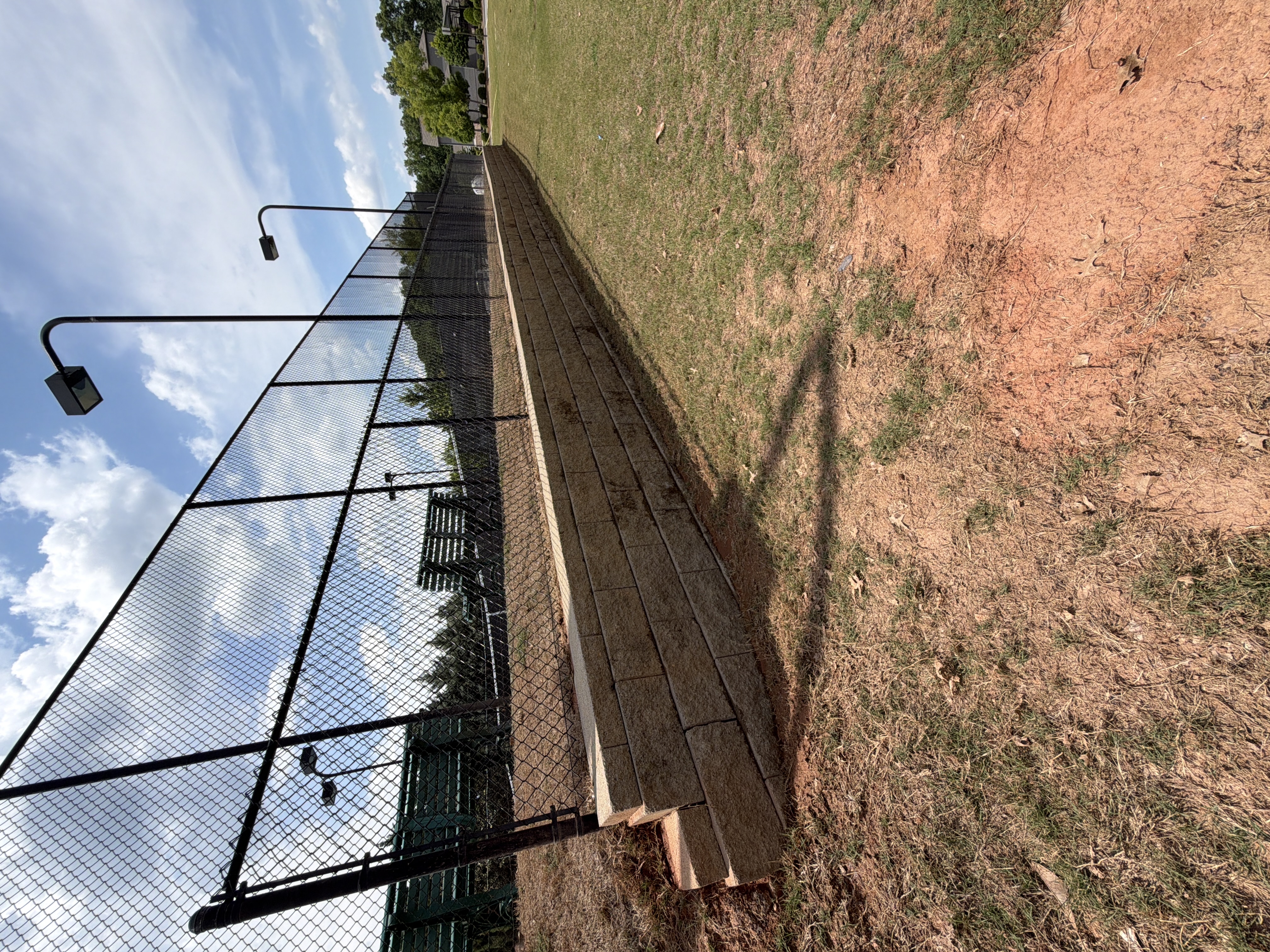 Stone retaining wall and black chain-link pool fence after pressure washing at a commercial property in Canton, GA, surface visibly cleaner