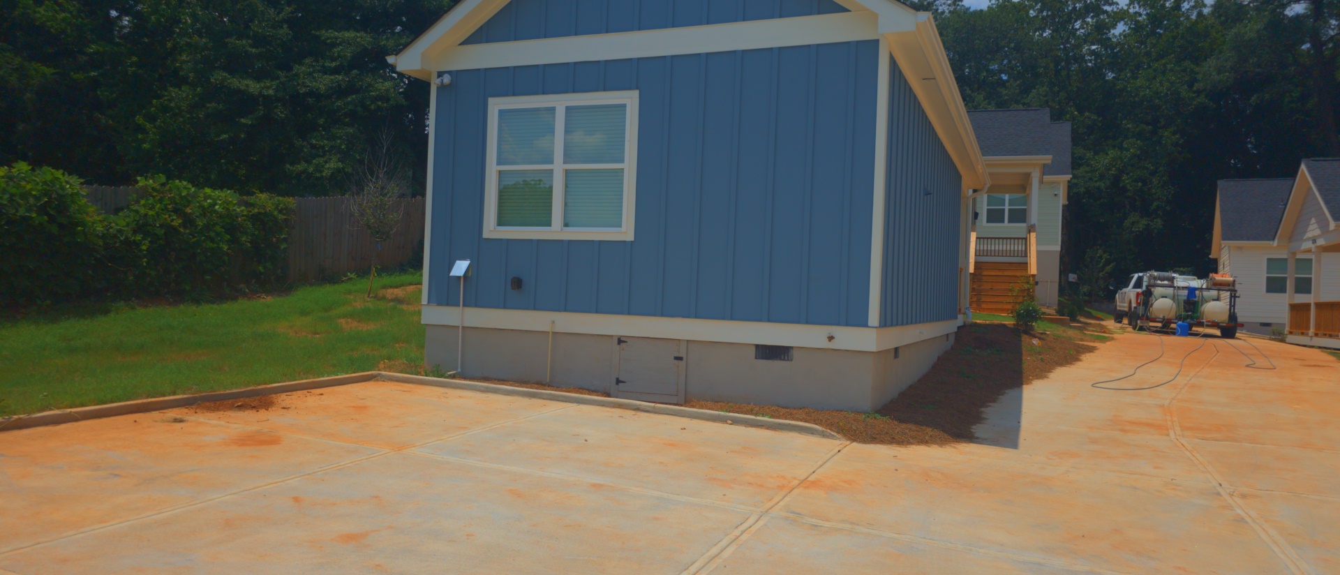 Wide concrete driveway pad in front of a blue board-and-batten new construction home at a pressure washing job in Atlanta, GA.