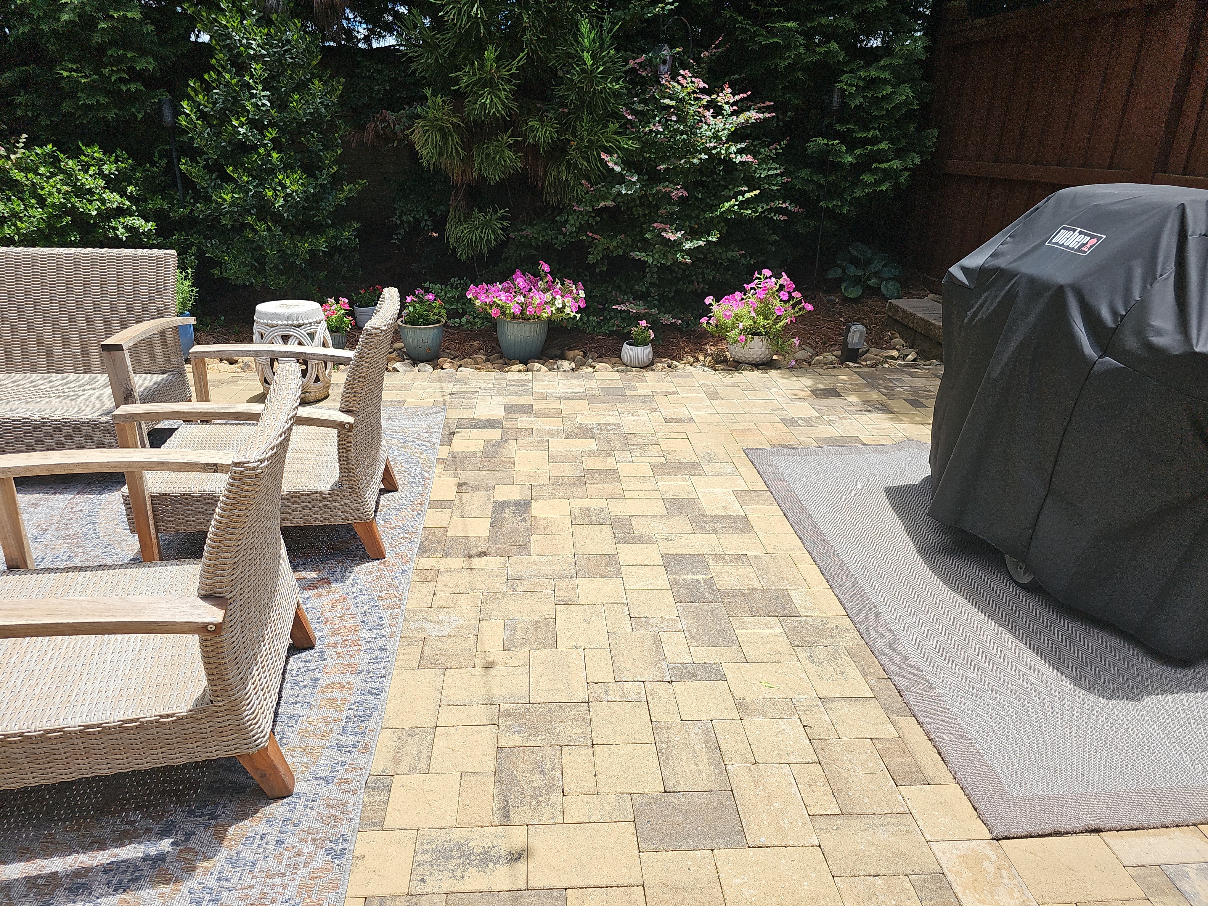 Backyard paver patio with wicker chairs, a covered grill, and flower beds at a residential job in Marietta, GA.