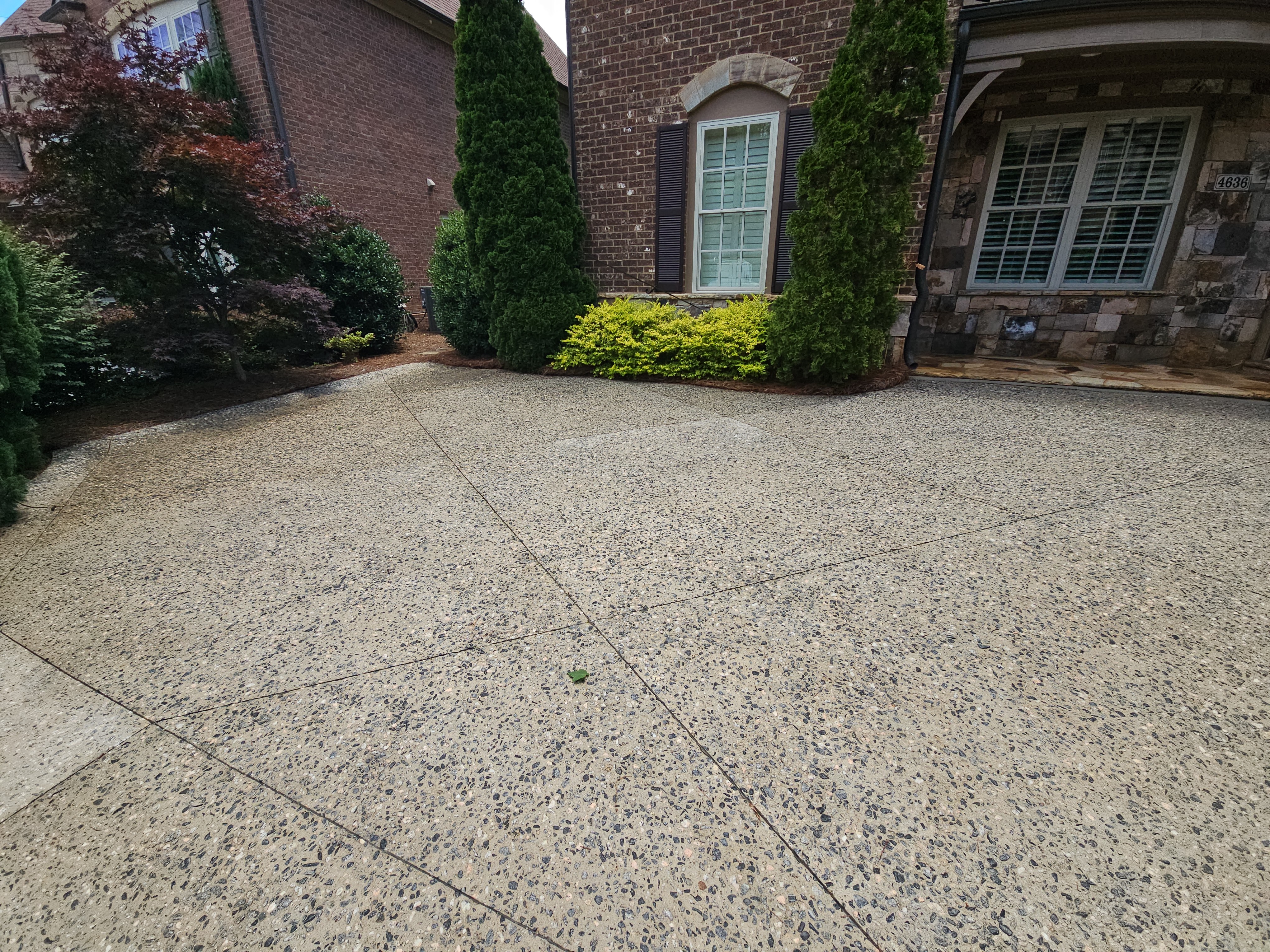 Wide exposed aggregate concrete driveway in front of a brick home in Marietta, GA.
