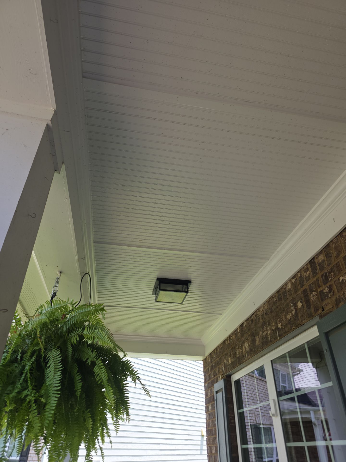 White beadboard porch ceiling with hanging fern and brick column at a Canton, GA home after a house wash.