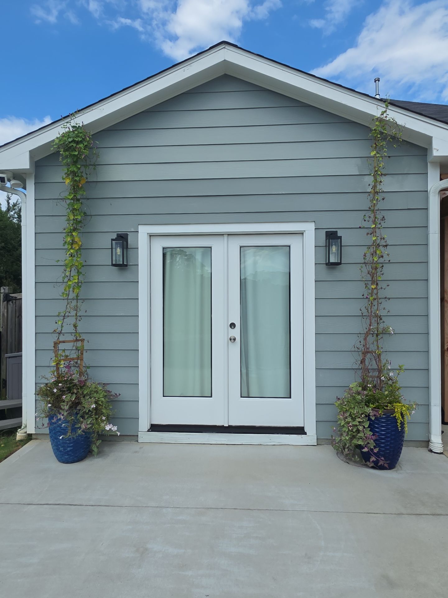 Rear gable of a gray vinyl-sided home with French doors and potted vines at a house washing job in Canton, GA.
