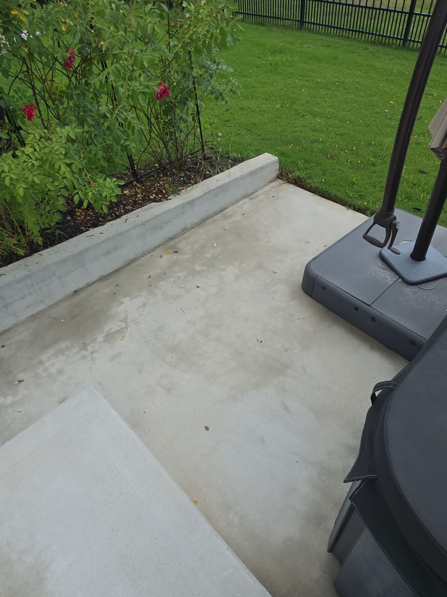 Close-up of a concrete patio surface and edge border beside a garden bed at a pressure washing job in Canton, GA.