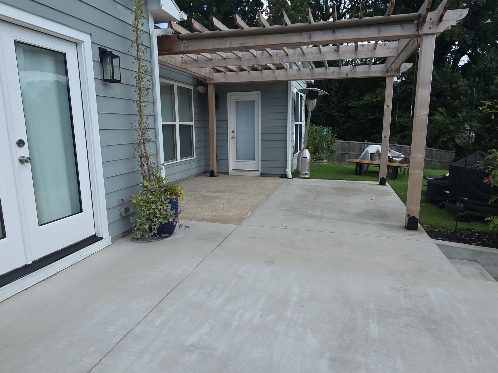 Wide concrete backyard patio under a wood pergola with French door entry at a pressure washing job in Canton, GA.