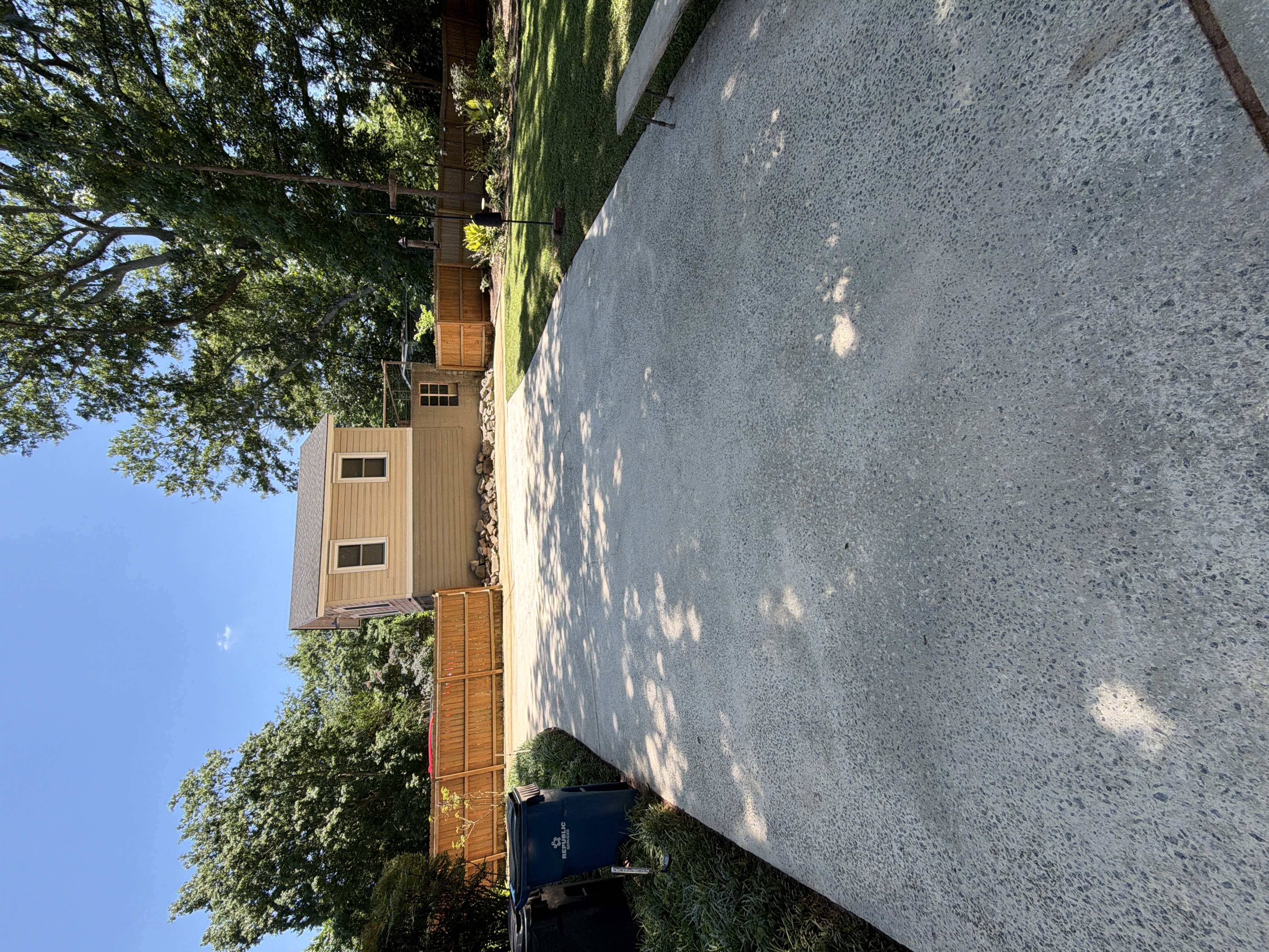 Rear concrete driveway pressure washed clean with open blue sky in East Point, GA