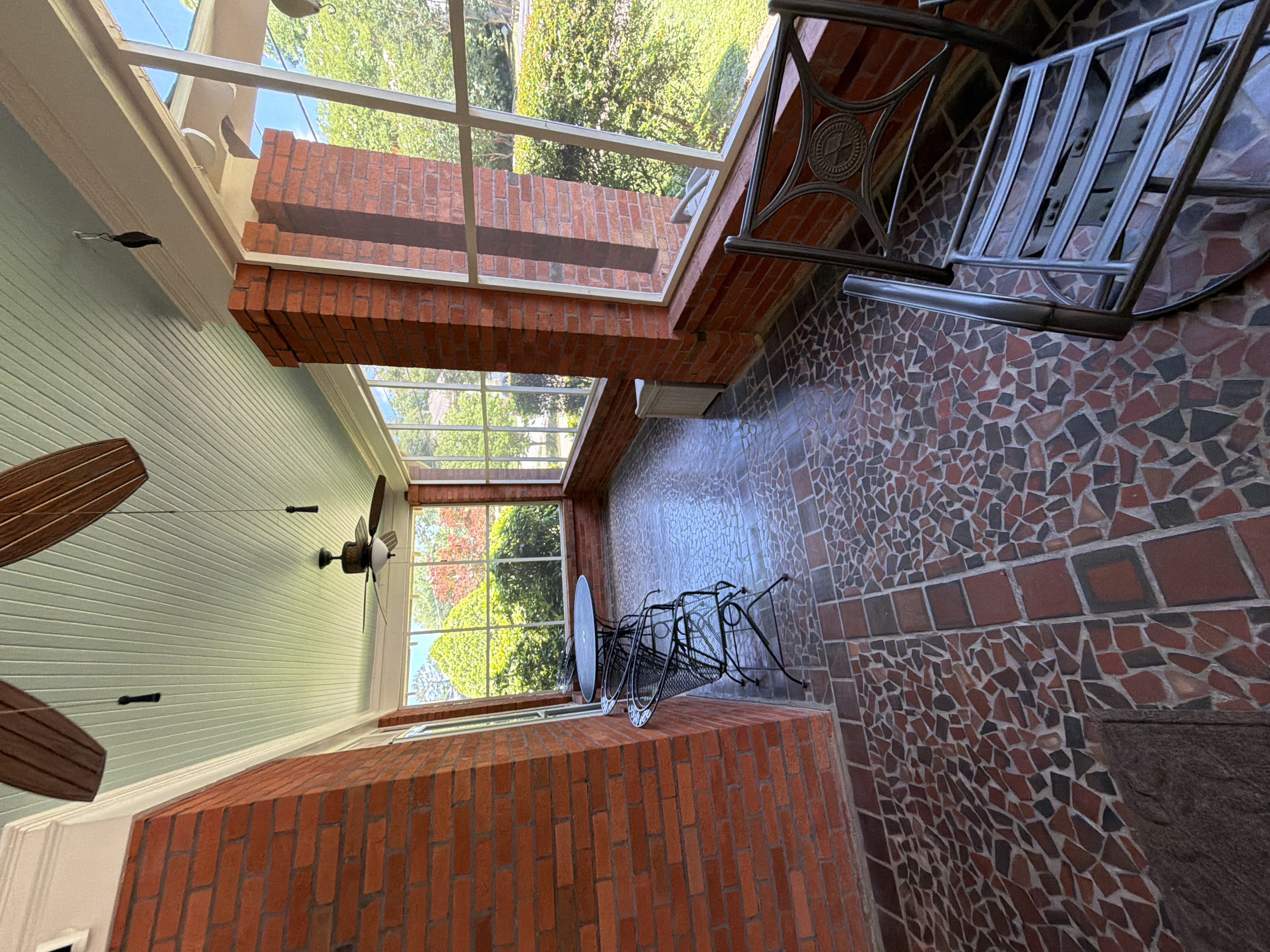 Screened porch with mosaic brick floor cleaned and chairs reset after pressure washing in East Point, GA