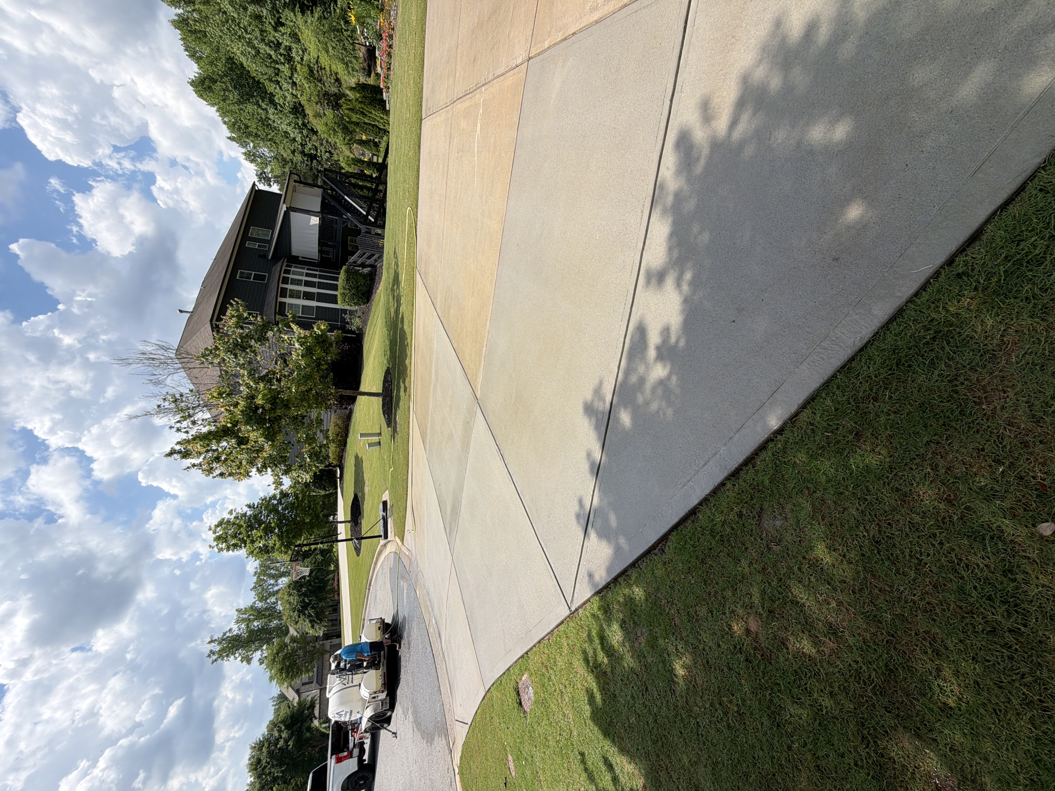 Concrete driveway pressure-washed in Canton, GA with Alpha Pressure Washing service truck and equipment trailer parked nearby, fully cleaned.