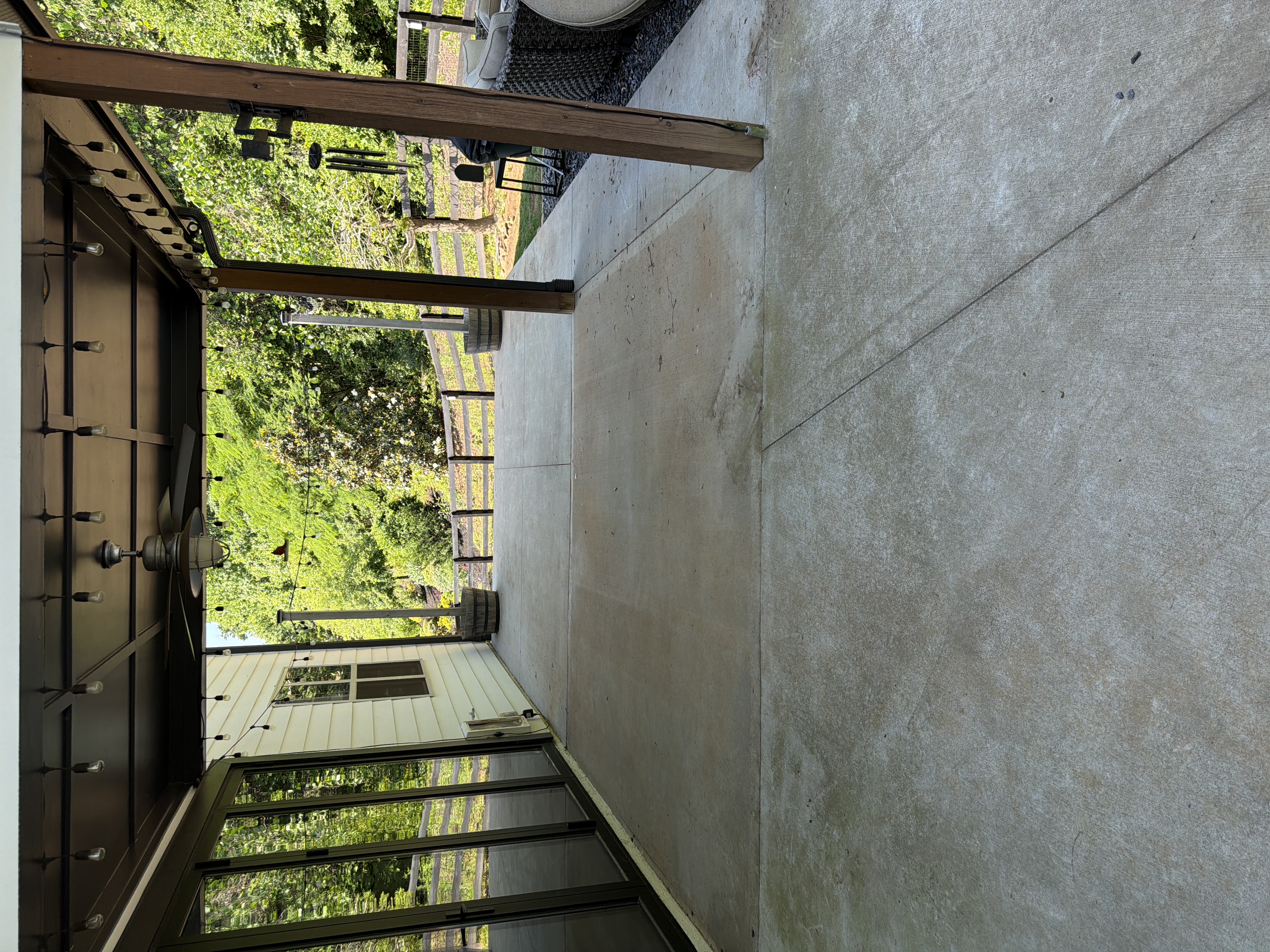Clean covered concrete patio after pressure washing in Canton, GA, looking outward through the pergola toward the fenced backyard