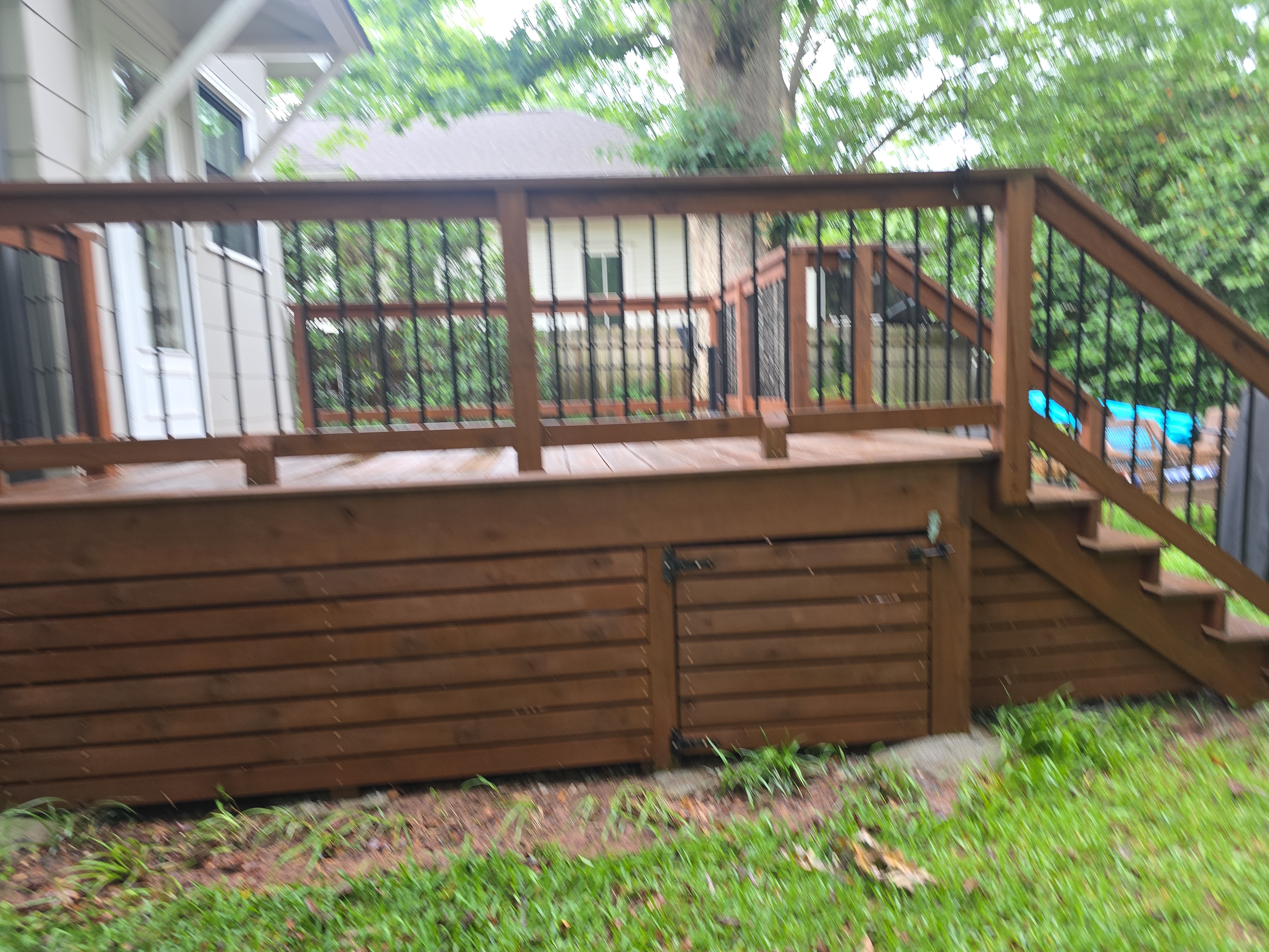 Wide view of clean wood deck with metal railings and under-deck skirting after pressure washing in East Point, GA
