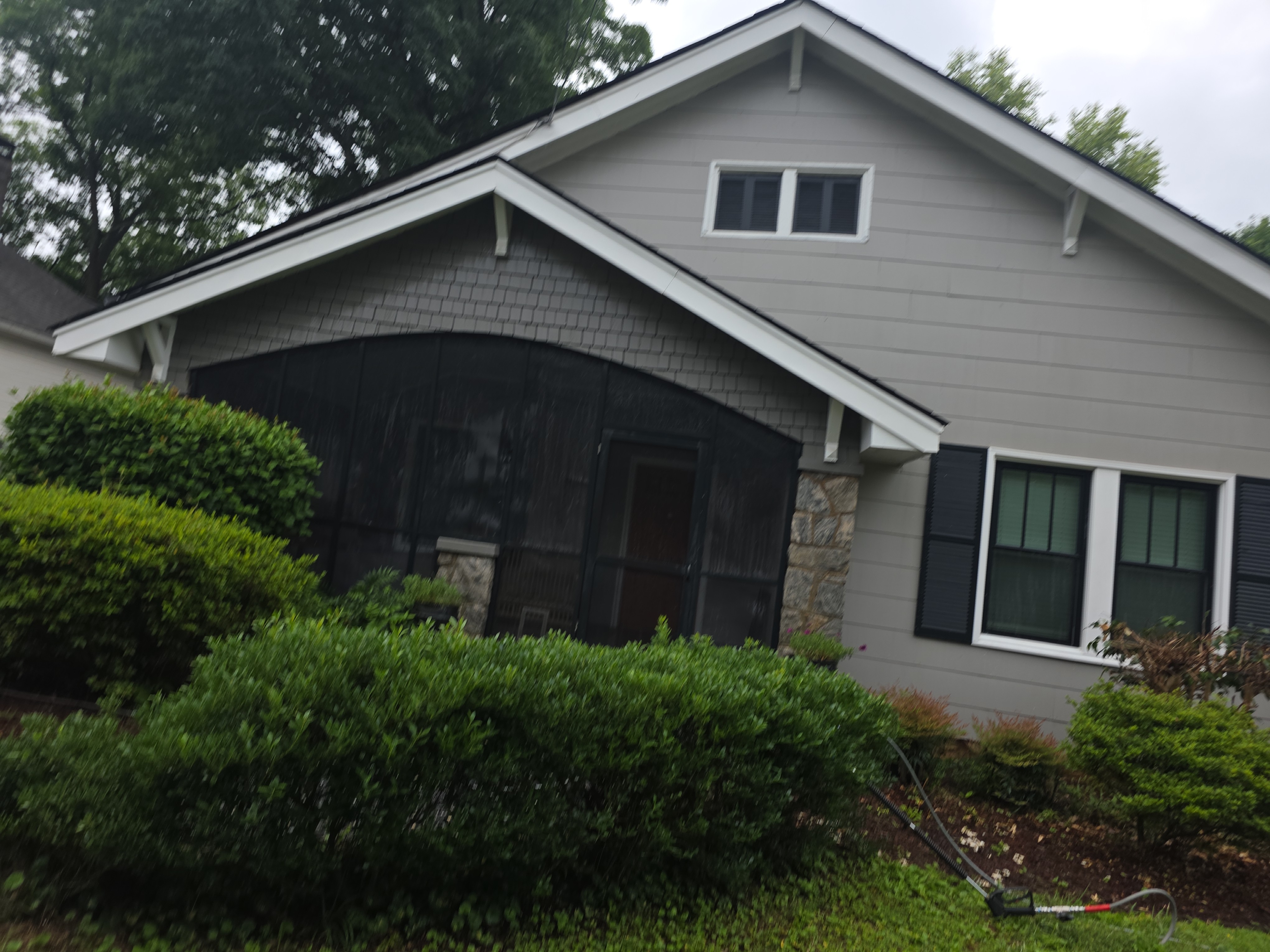 Gray vinyl siding and screened front porch on a craftsman-style home after house washing in East Point, GA
