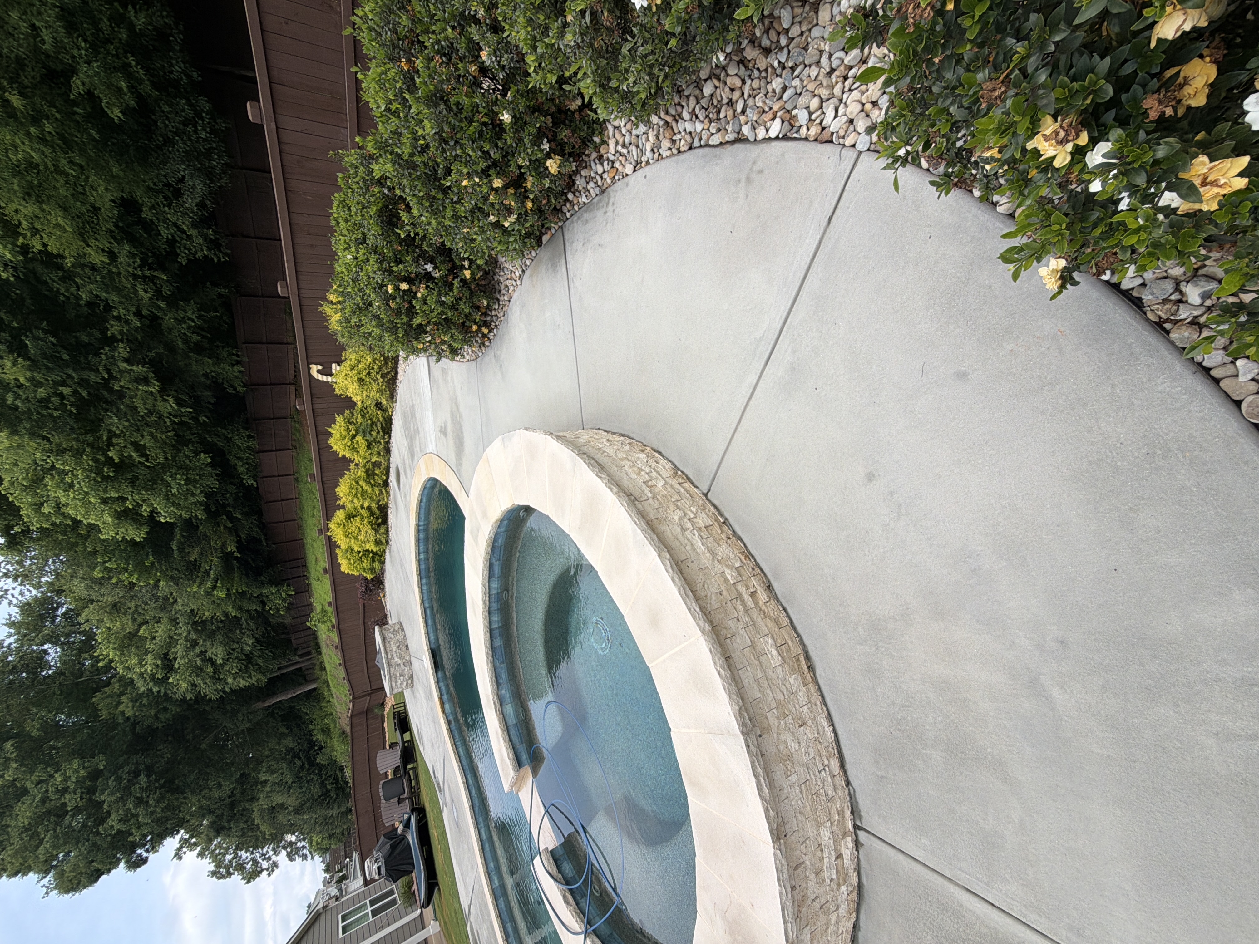 Freshly pressure-washed concrete pool deck wrapping around elevated spa in Canton, GA backyard