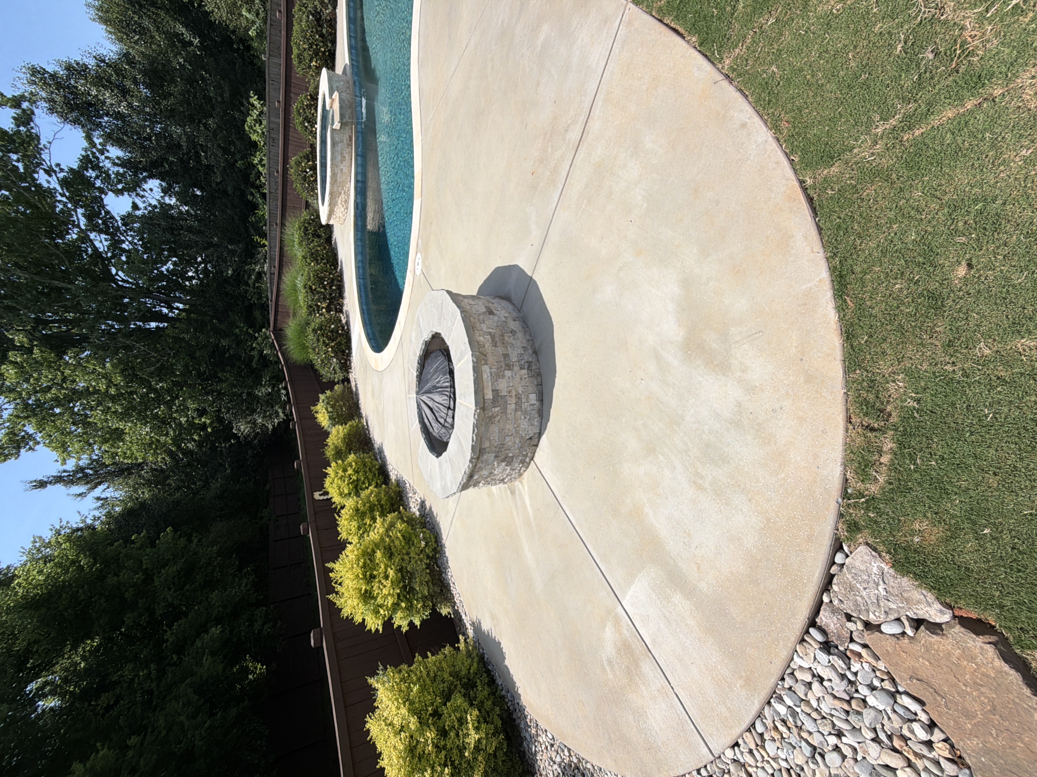 Wide view of clean concrete pool deck with stone fire pit after pressure washing service in Canton, GA