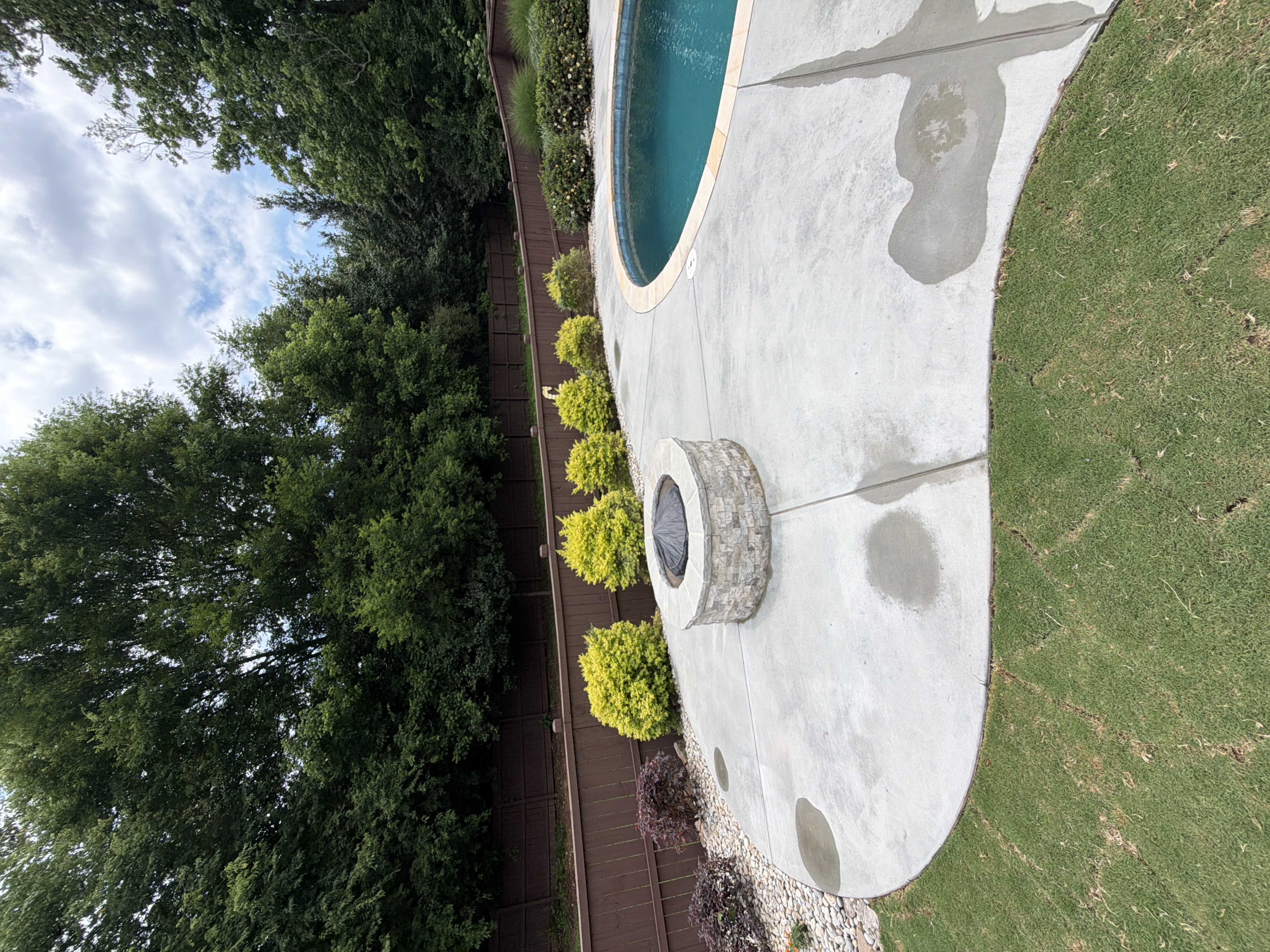 Wide-angle view of clean concrete pool deck and stone fire pit after pressure washing in Canton, GA