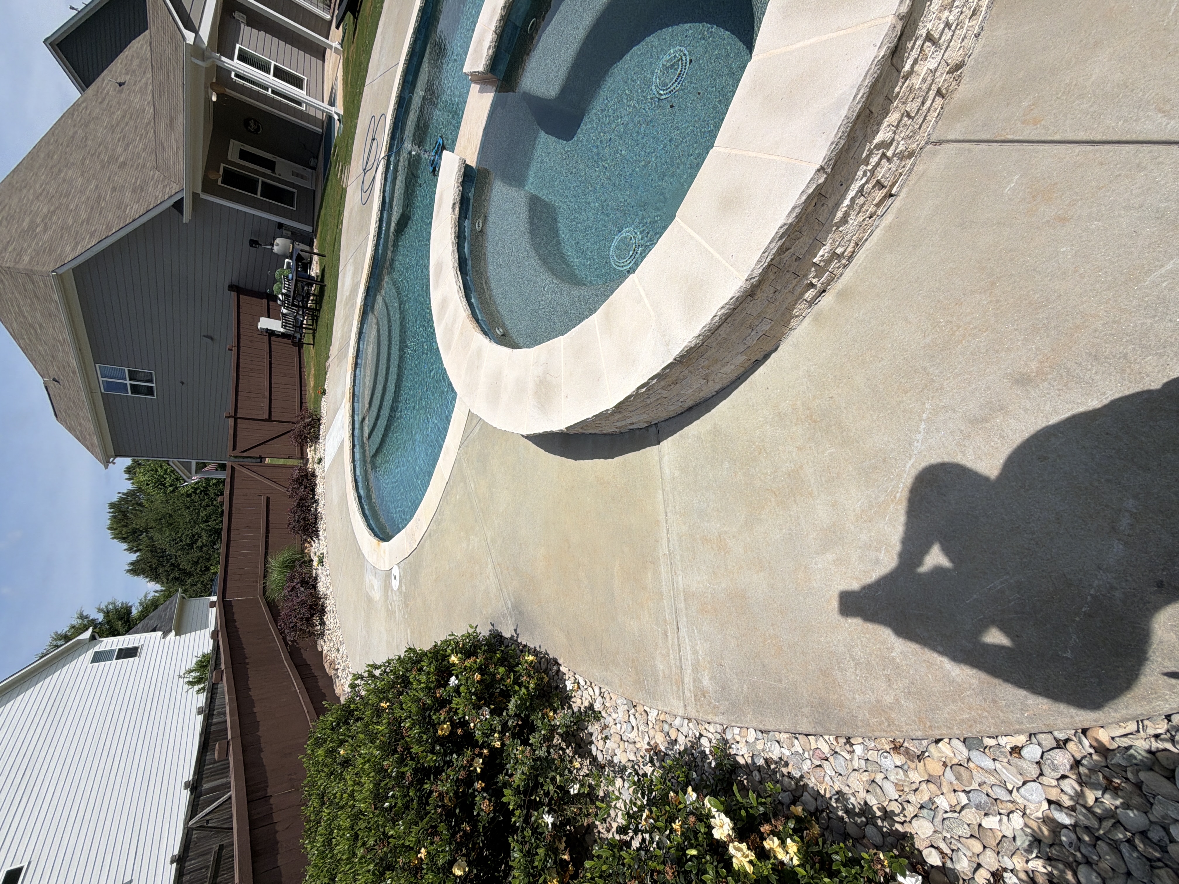 Clean concrete pool deck and elevated spa after pressure washing in Canton, GA, natural stone coping gleaming