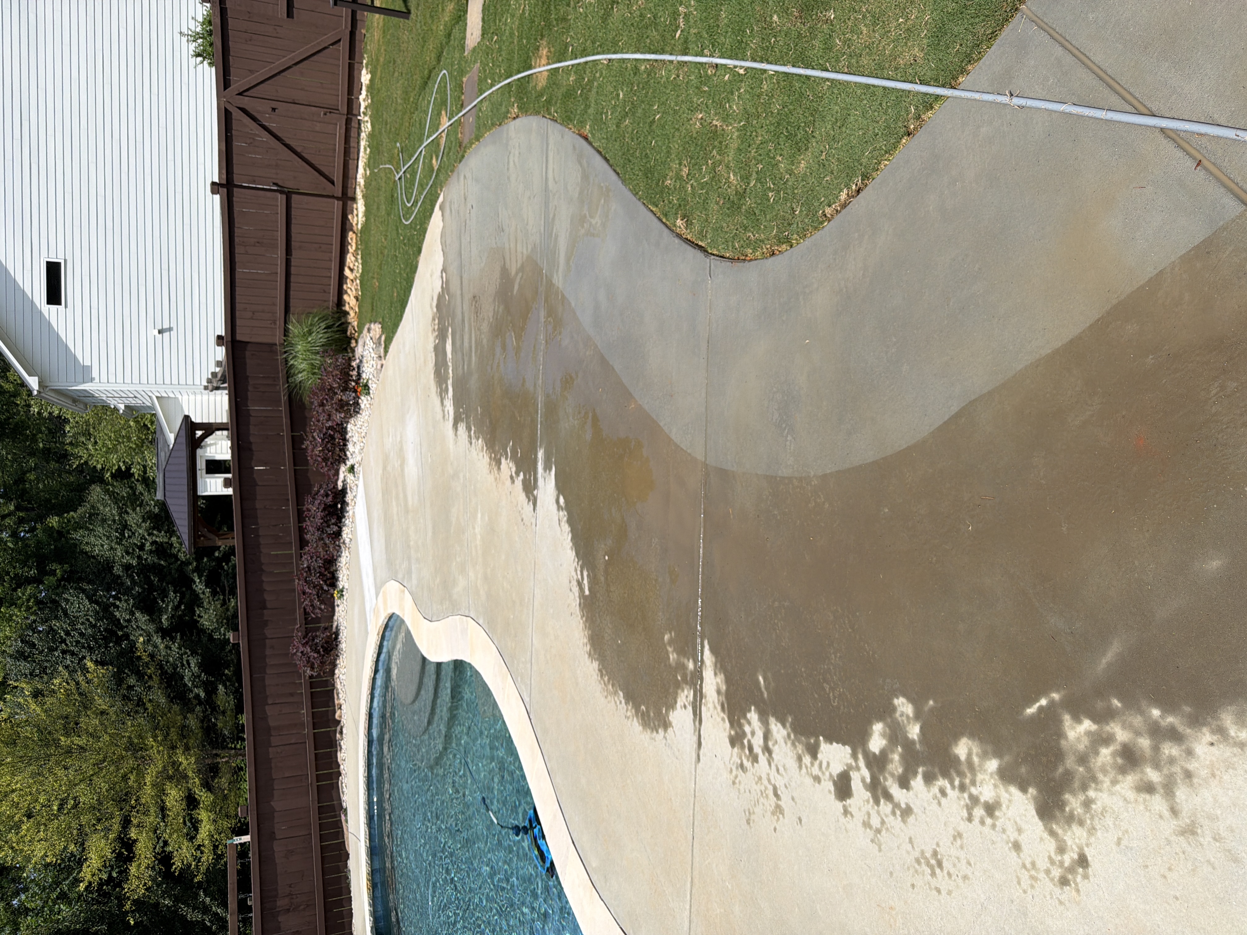 Concrete pool deck mid-clean during pressure washing in Canton, GA, showing half-cleaned surface beside the pool