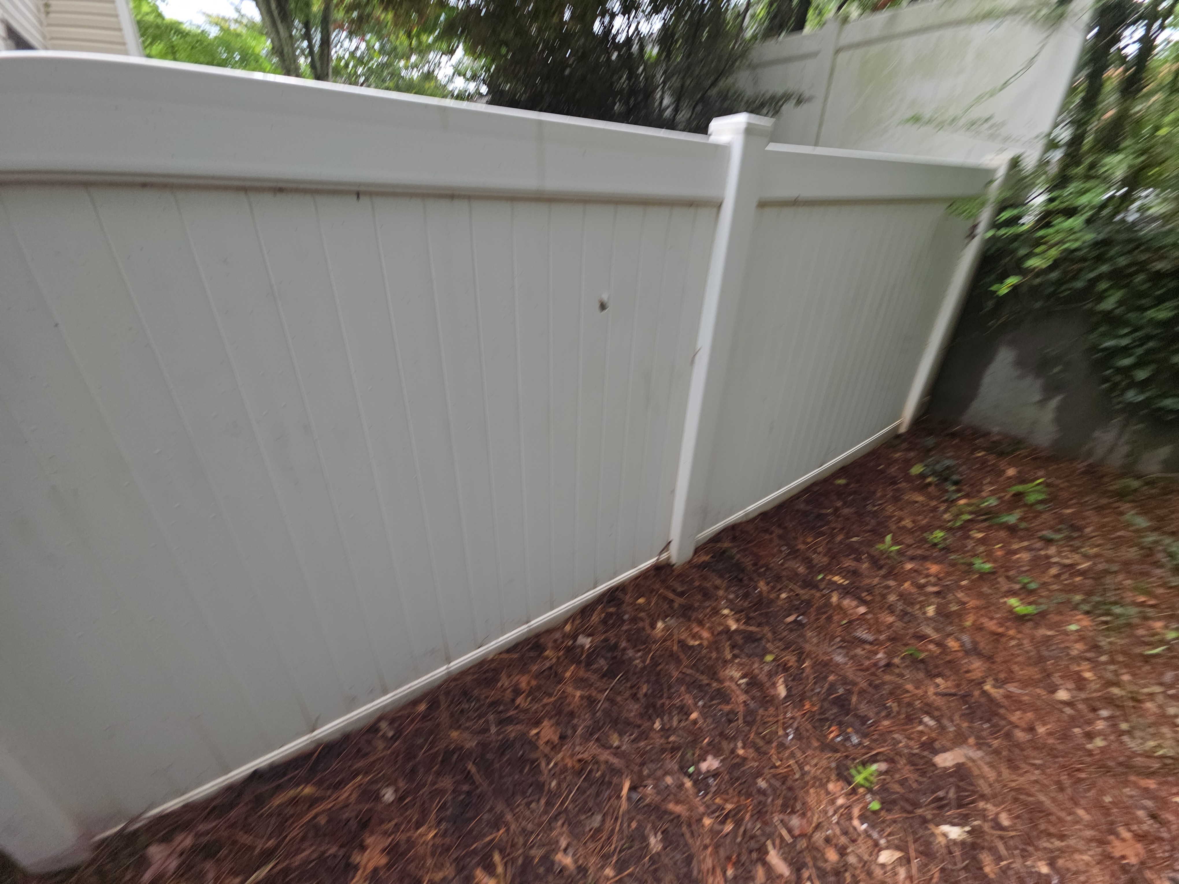 White vinyl privacy fence panels along a mulch bed at a fence cleaning job in Woodstock, GA.
