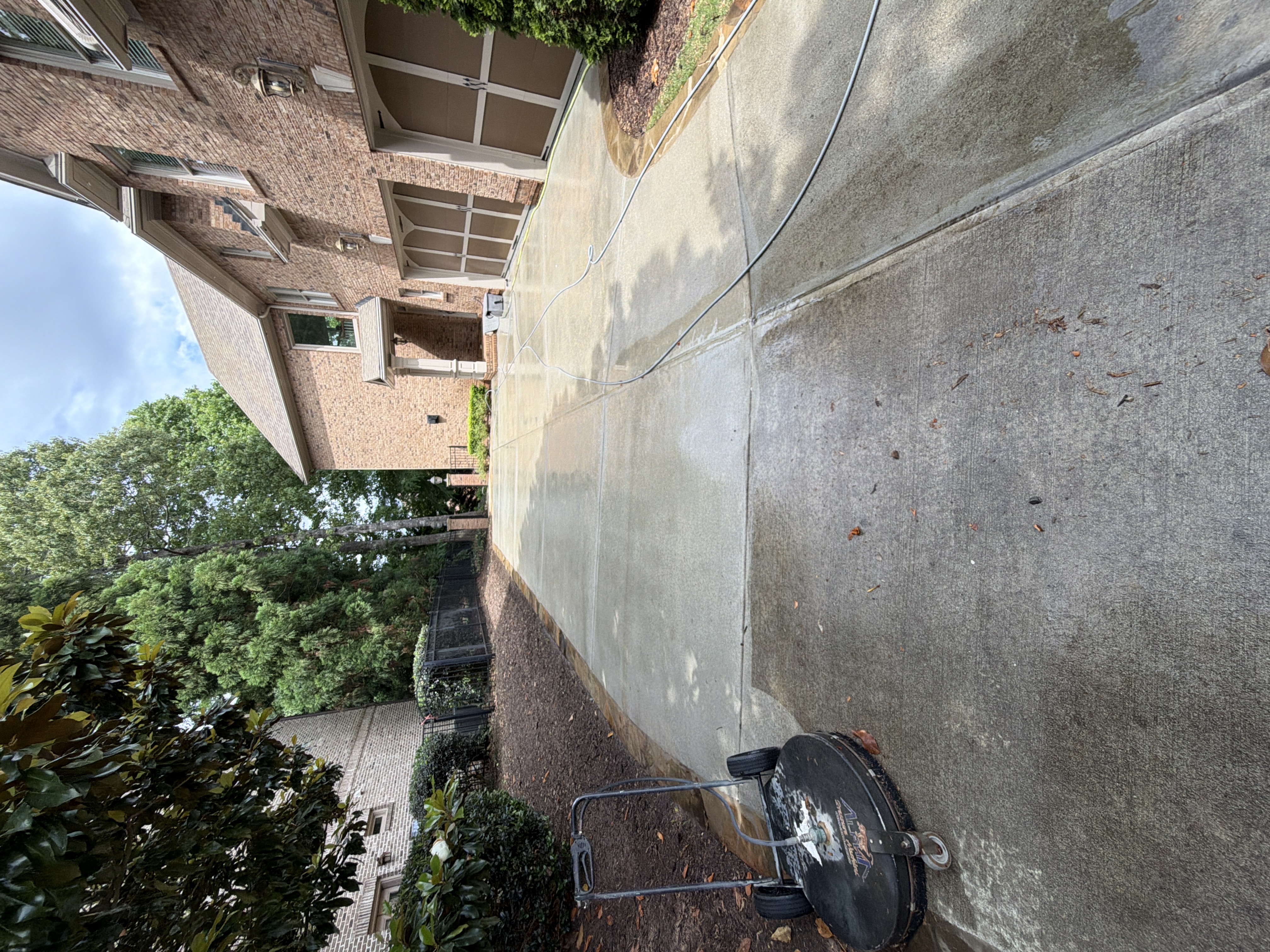 Concrete driveway being cleaned with a rotary surface cleaner during a pressure washing job at a Duluth, GA home.