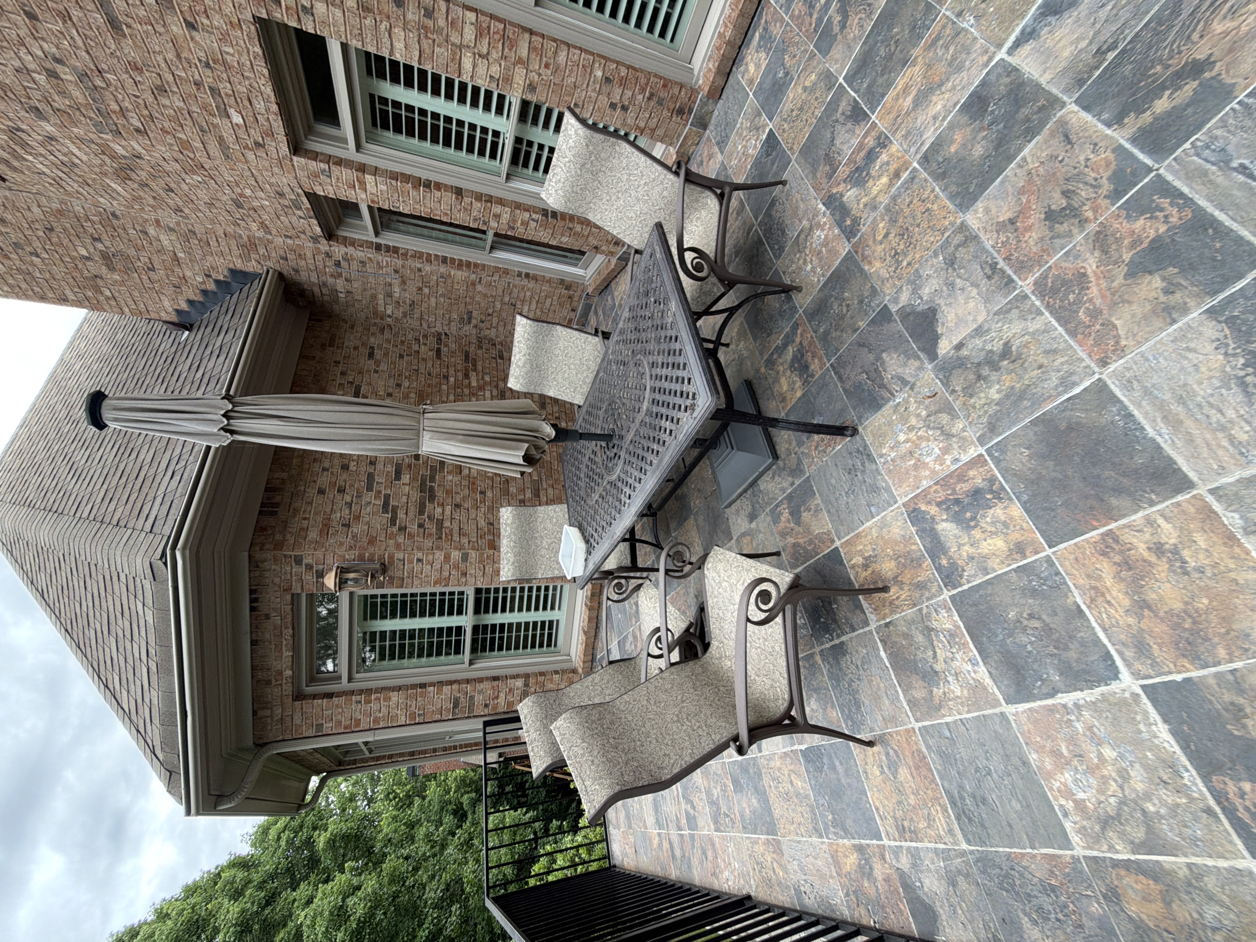Upper tile deck with metal dining set and umbrella at a Duluth, GA residential pressure washing job.
