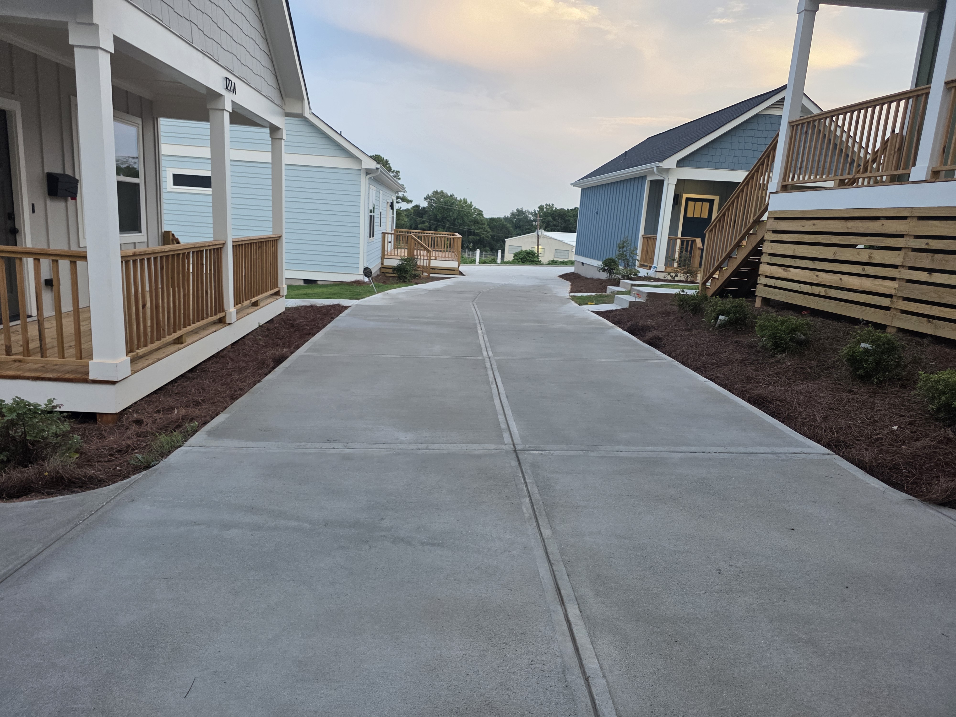 Concrete driveway running between multiple new construction homes after pressure washing in Atlanta, GA, at dusk.
