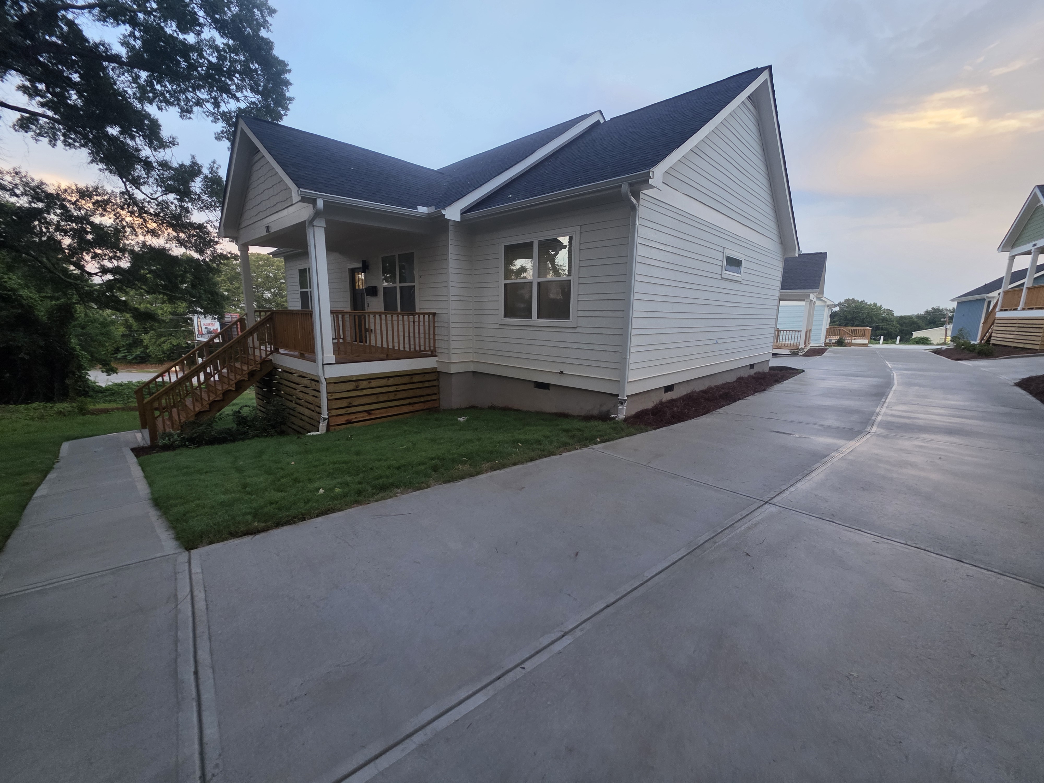 Newly constructed home with white vinyl siding and wood porch beside a concrete driveway after pressure washing in Atlanta, GA.