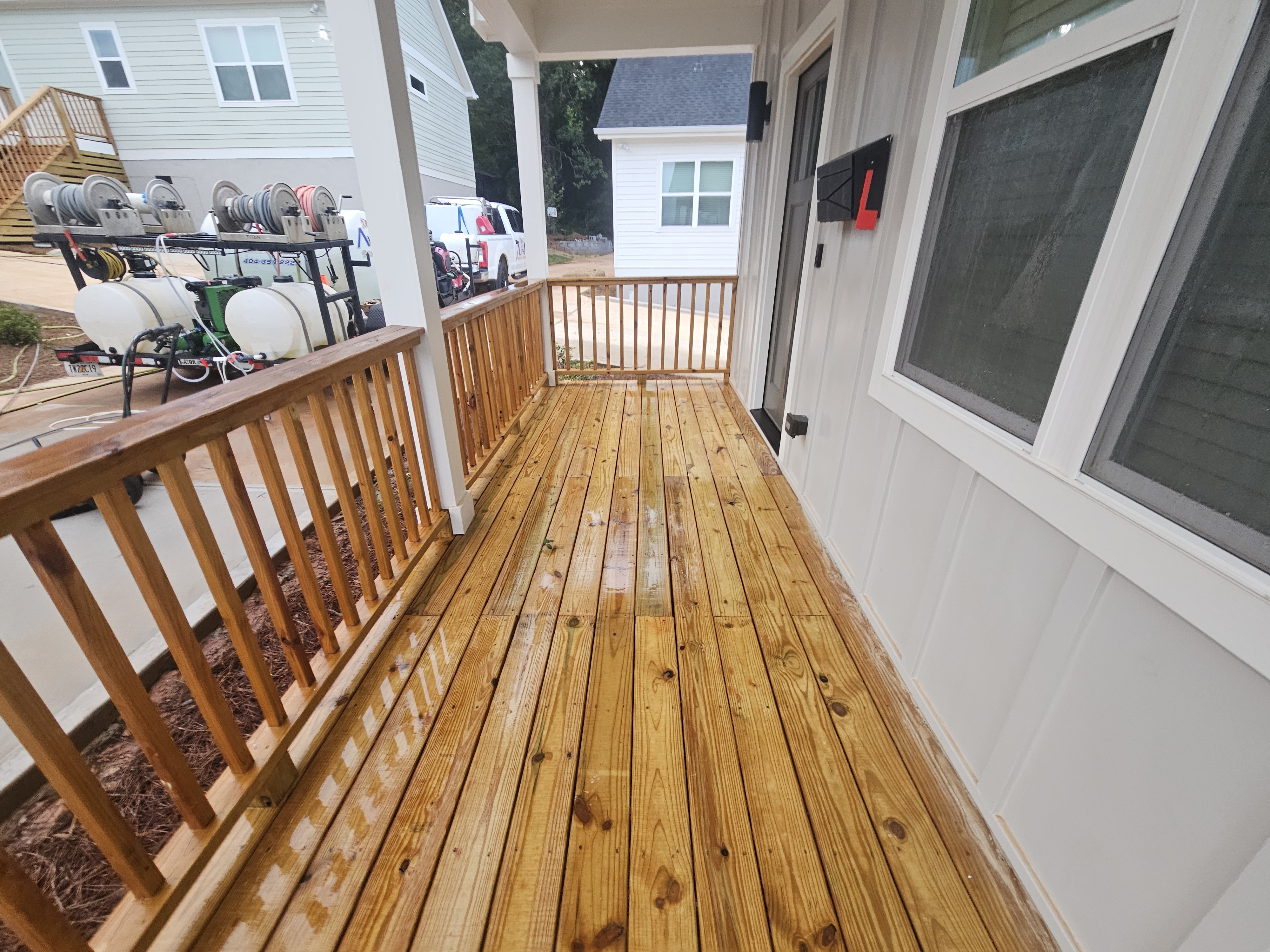 Wood porch deck during pressure washing with equipment visible in background at a new construction job in Atlanta, GA.