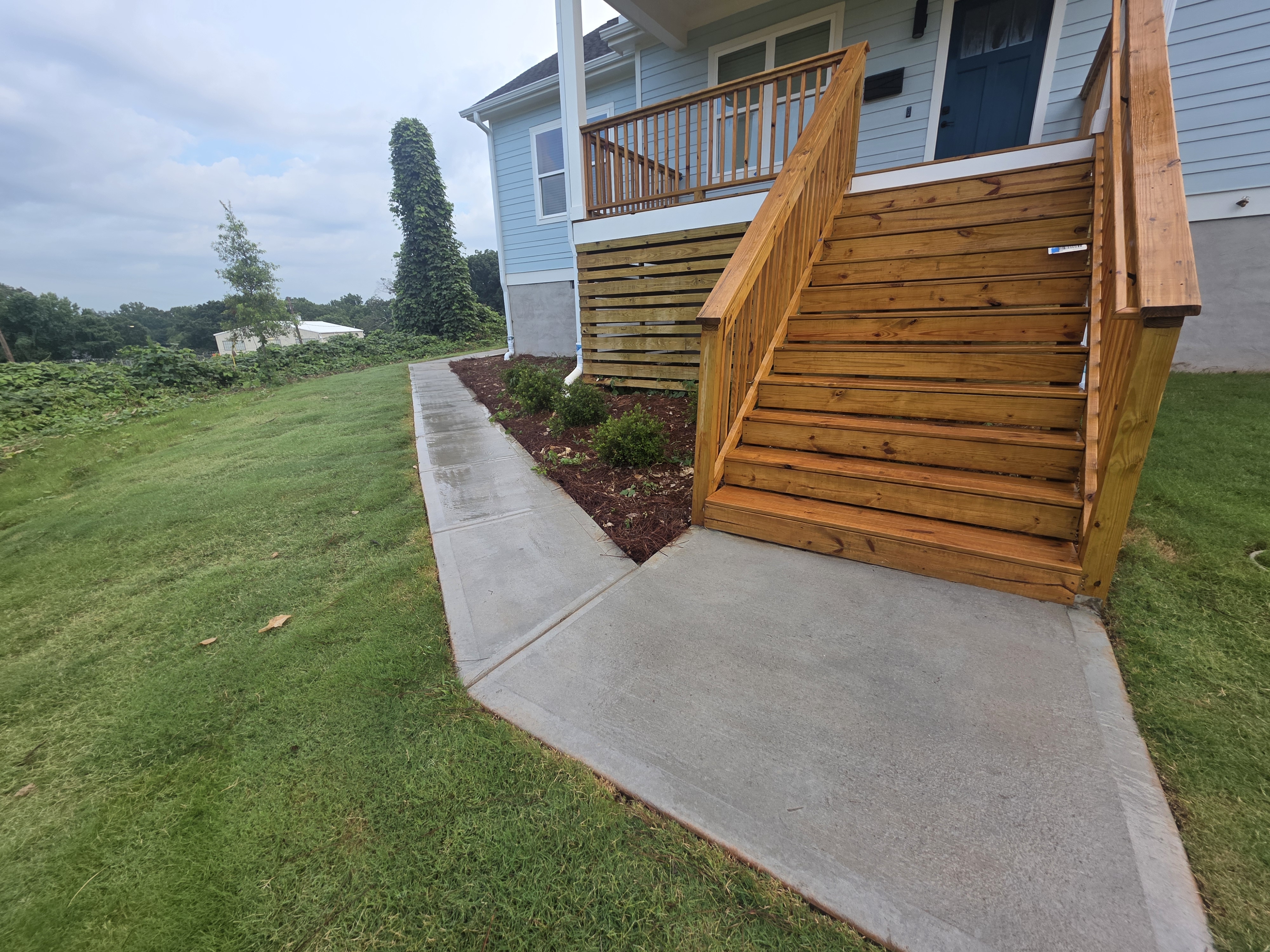 Concrete sidewalk beside a wood deck staircase at a new construction pressure washing job in Atlanta, GA.