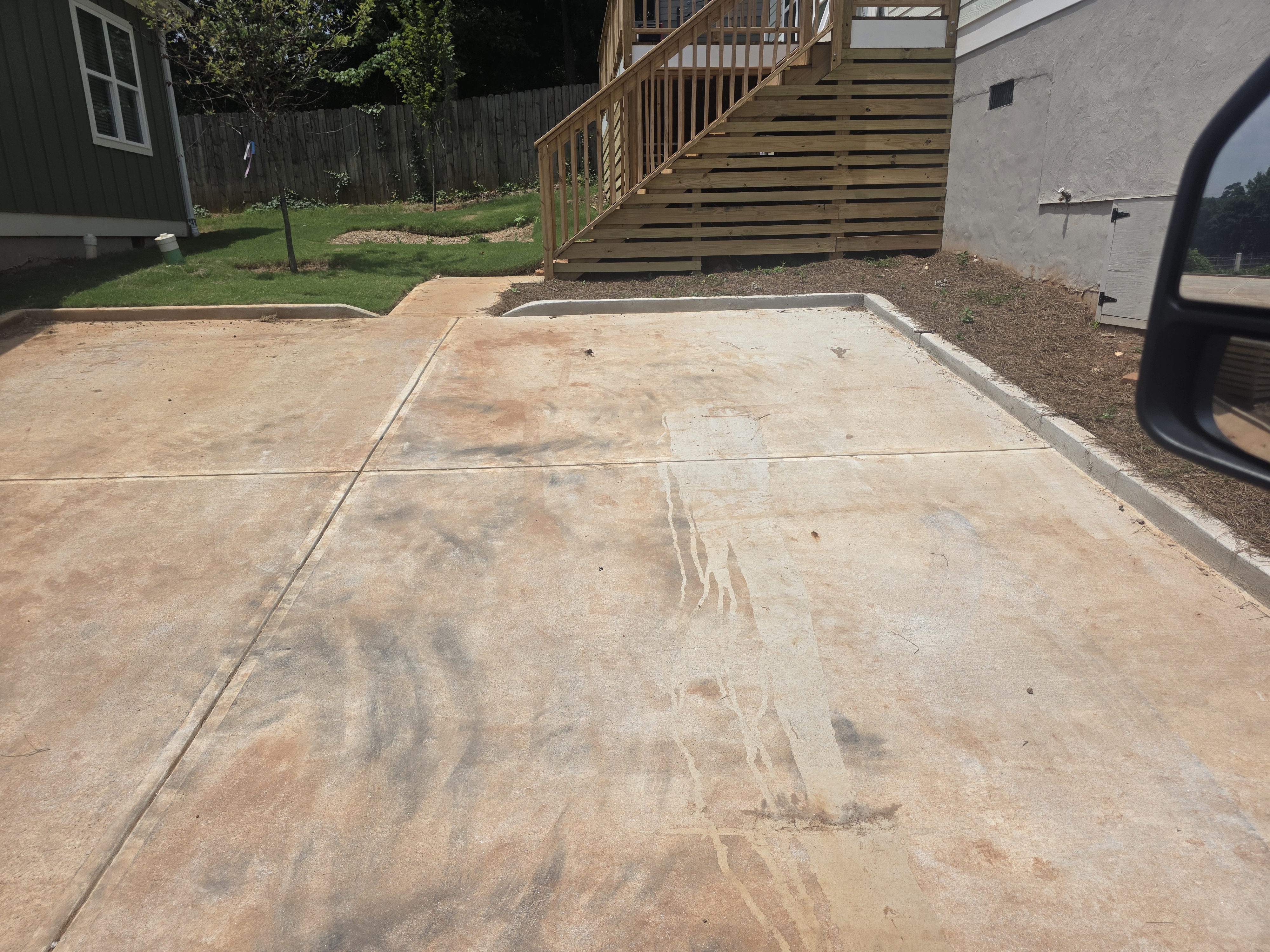 Concrete driveway pad and wood deck staircase at the rear of a new construction home in Atlanta, GA.