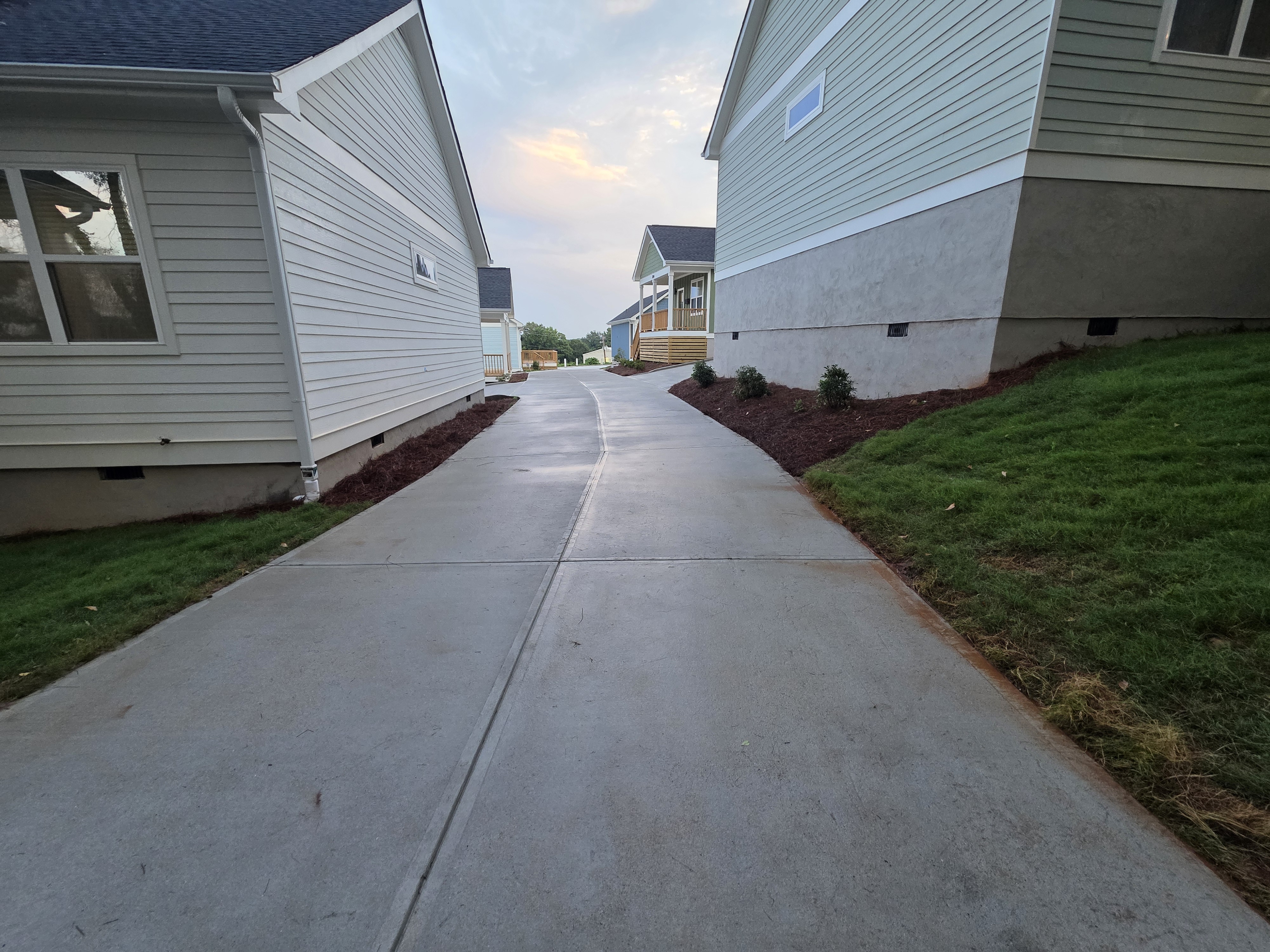 Concrete driveway between new construction homes after pressure washing in Atlanta, GA, at dusk.