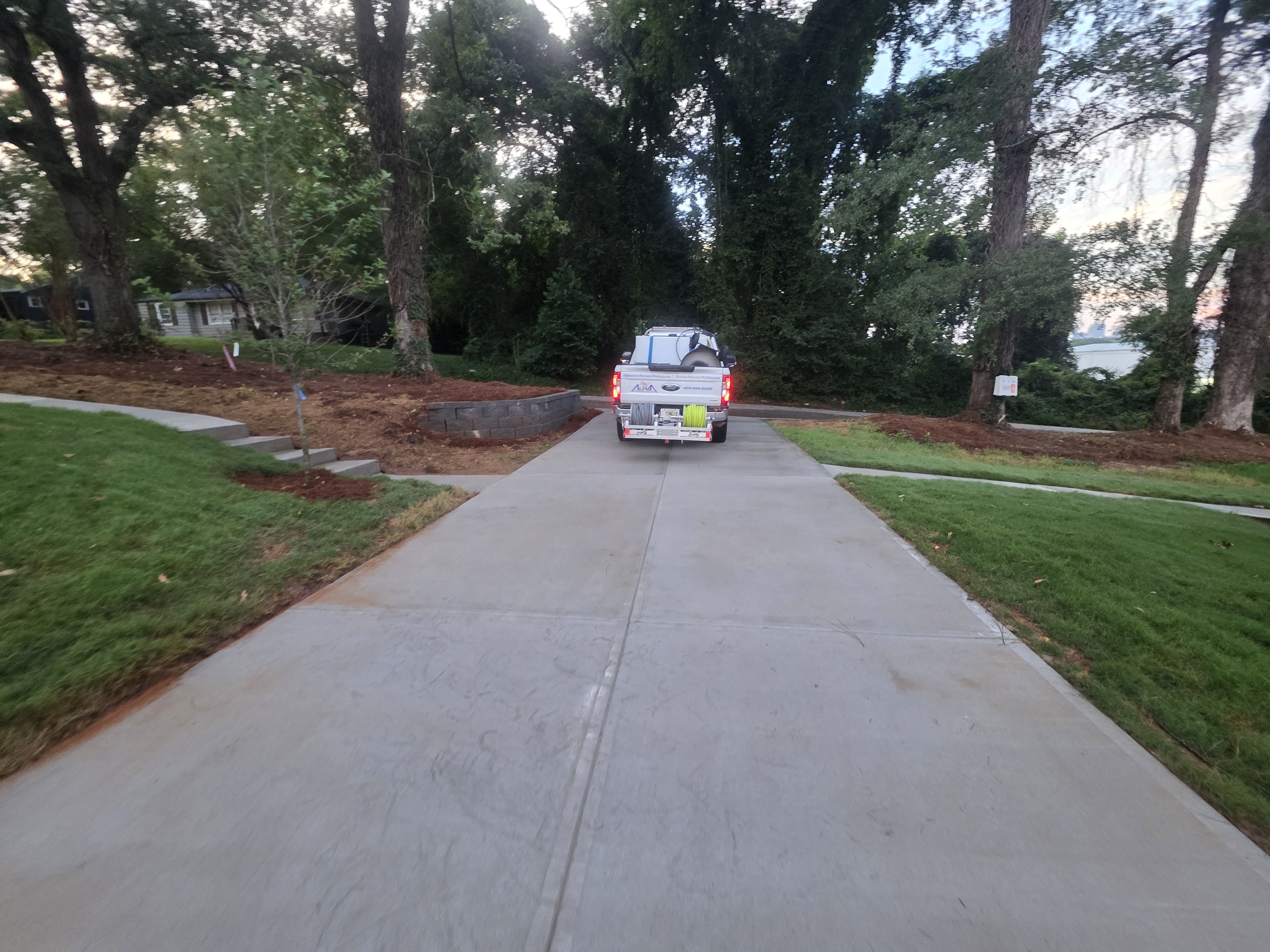 Concrete driveway at dusk with pressure washing truck departing after a new construction wash job in Atlanta, GA.