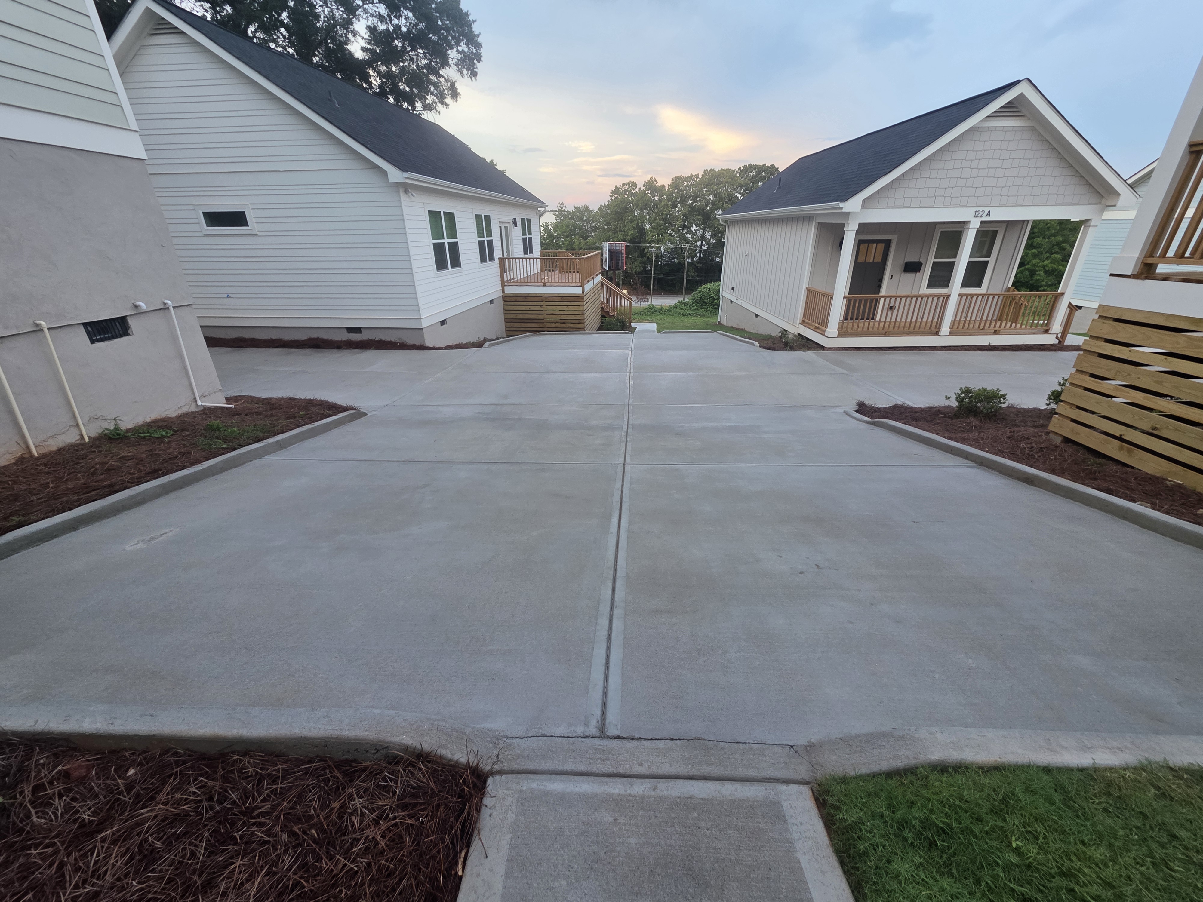 Wide concrete driveway between new construction homes photographed at dusk after pressure washing in Atlanta, GA.