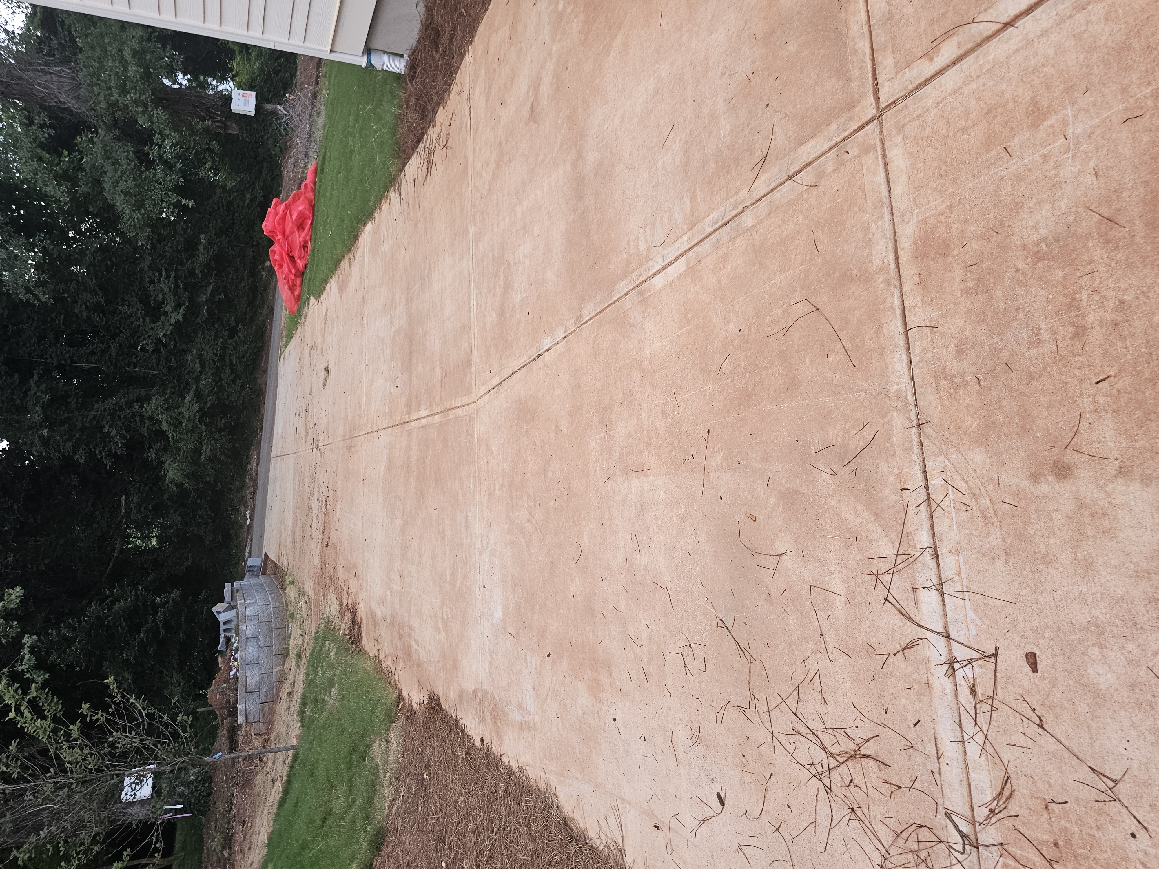 Concrete driveway with pine needles and debris before pressure washing at a new construction site in Atlanta, GA.