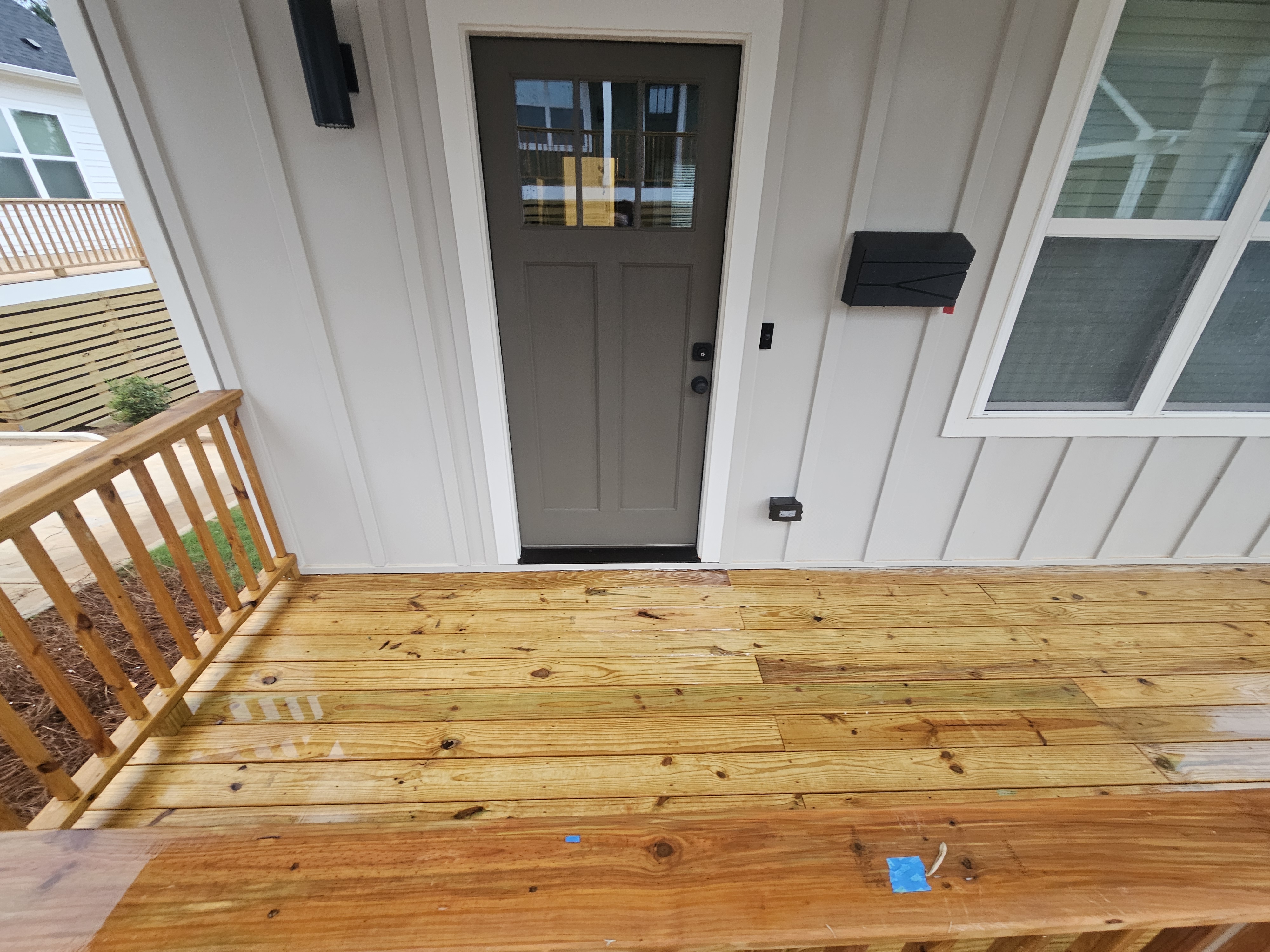 Wet wood porch deck in front of an entry door during a new construction wash in Atlanta, GA.