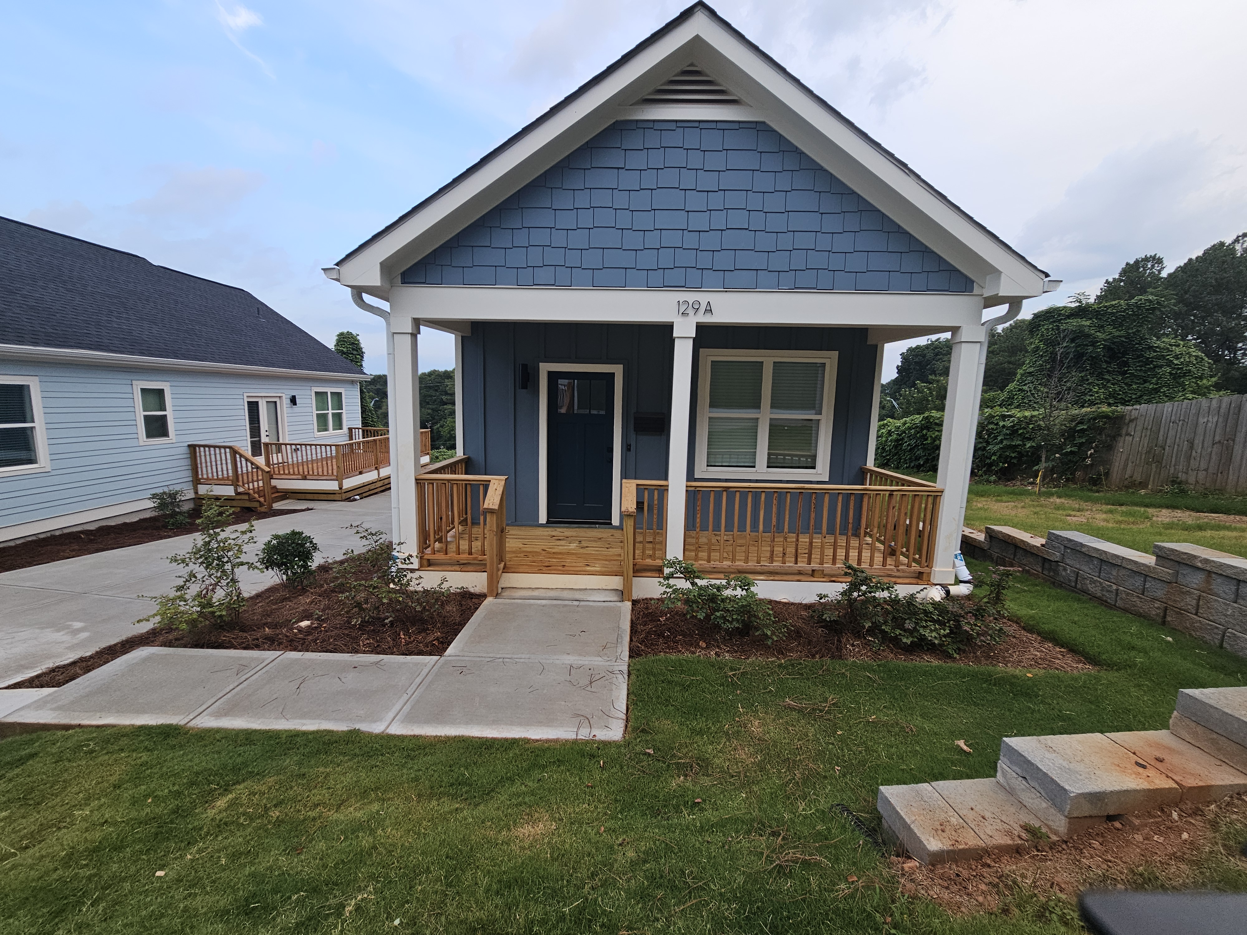 Front elevation of a newly constructed cottage home with blue siding and wood porch at a pressure washing job in Atlanta, GA.