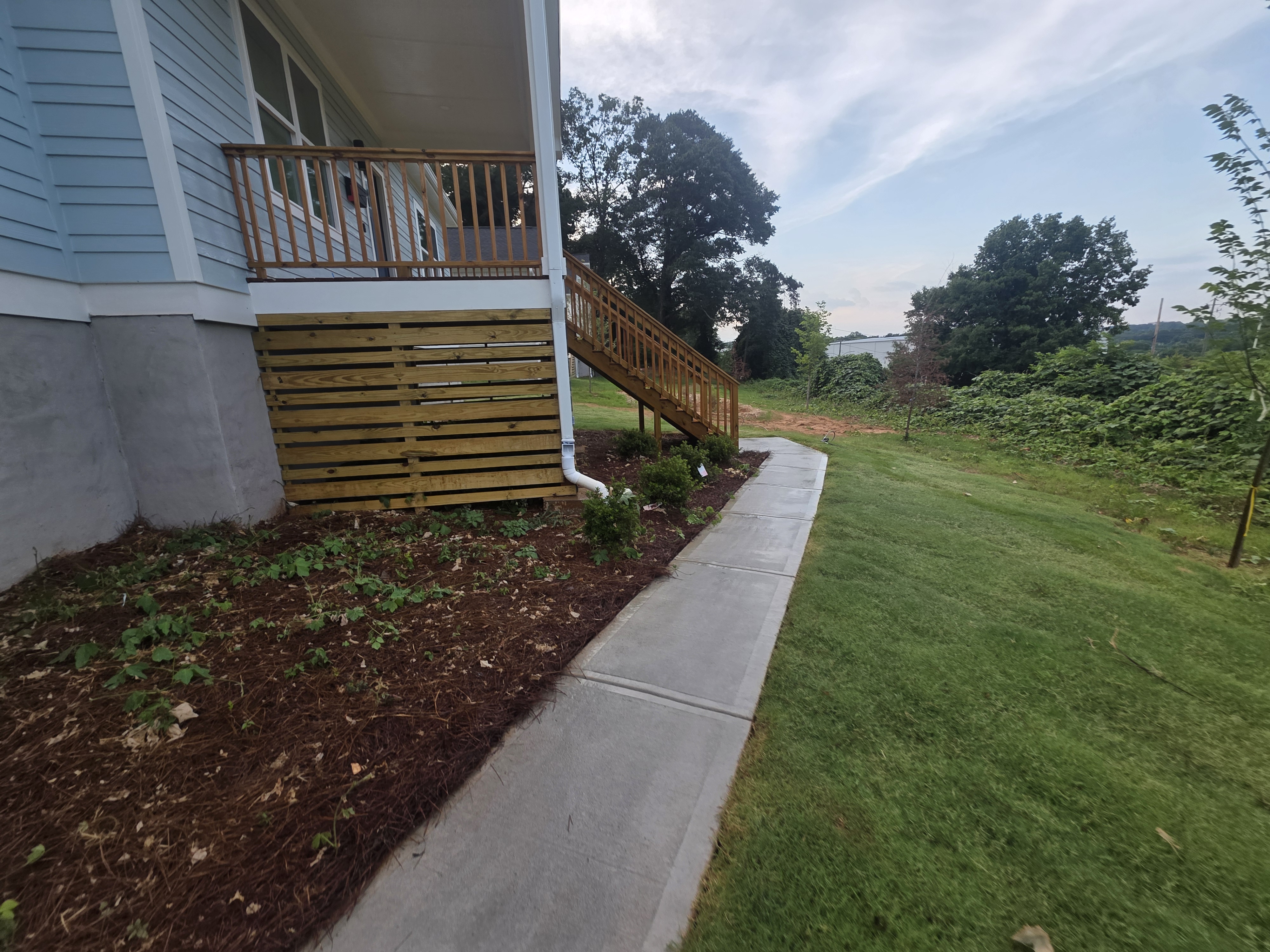 Concrete walkway along the side of a new construction home with wood deck at a pressure washing job in Atlanta, GA.