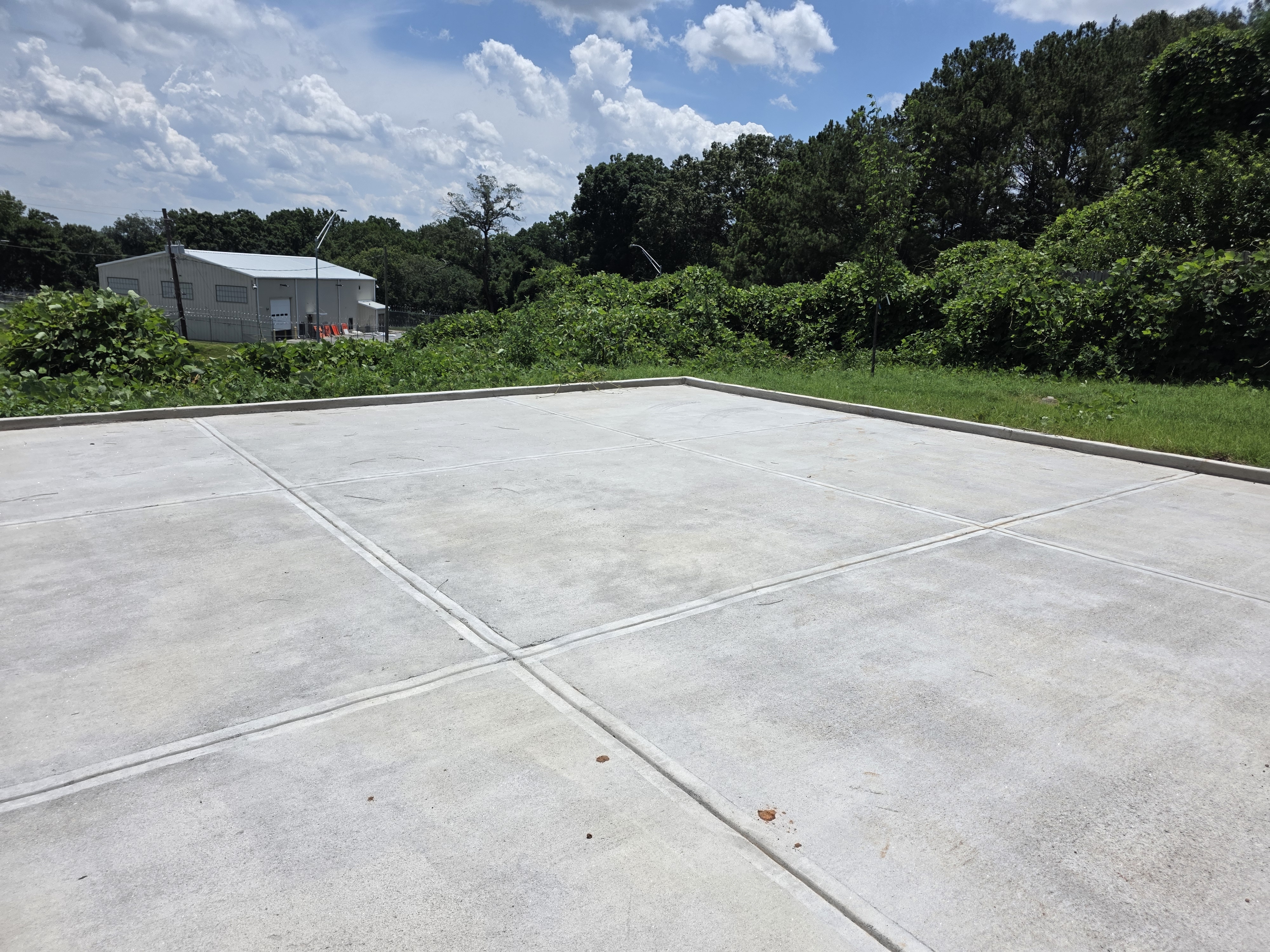 Large concrete pad at the rear of a new construction home after pressure washing in Atlanta, GA, under bright sky.