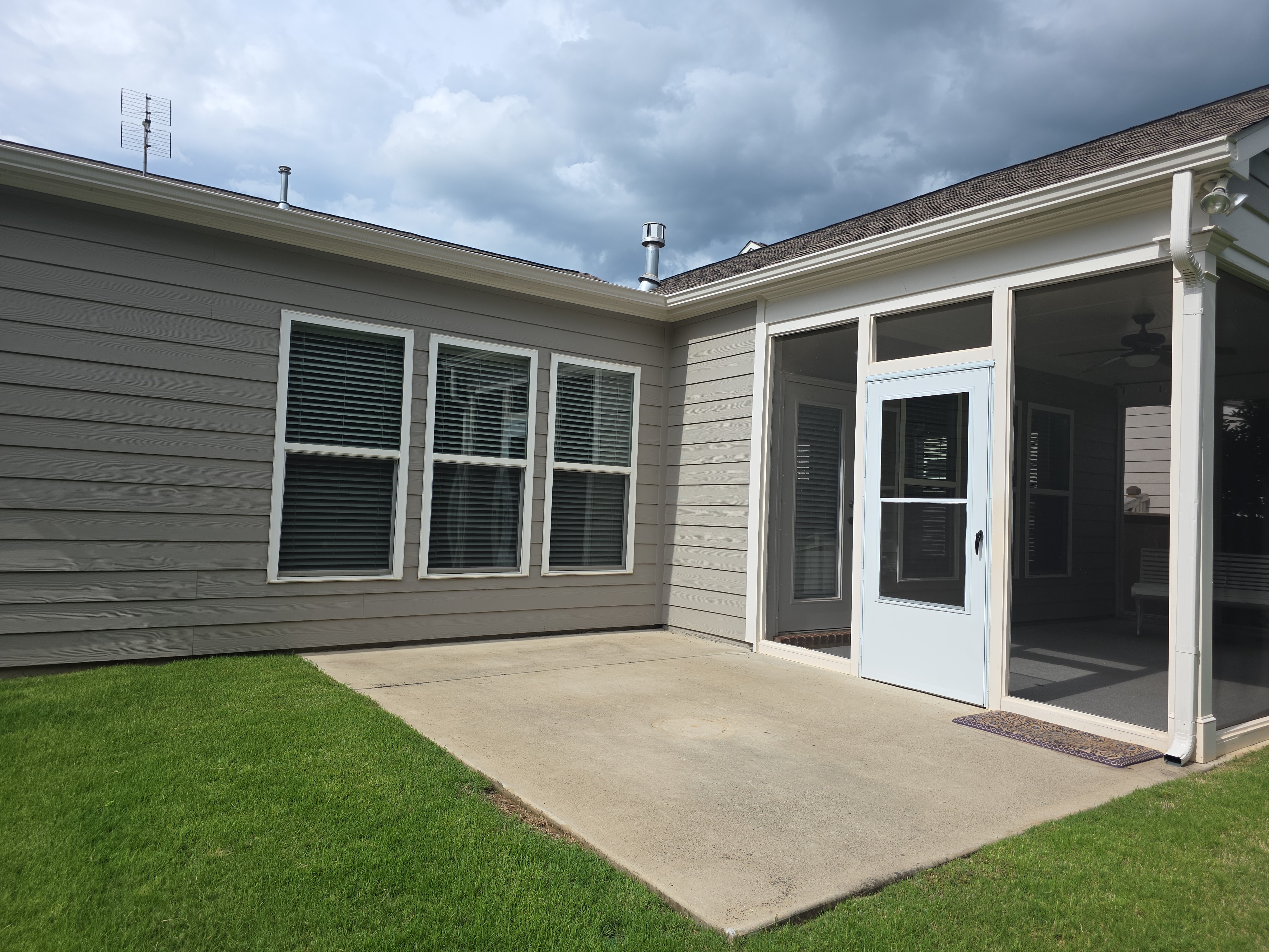 Concrete back patio and screened porch exterior before pressure washing in Woodstock, GA, showing surface grime ahead of listing