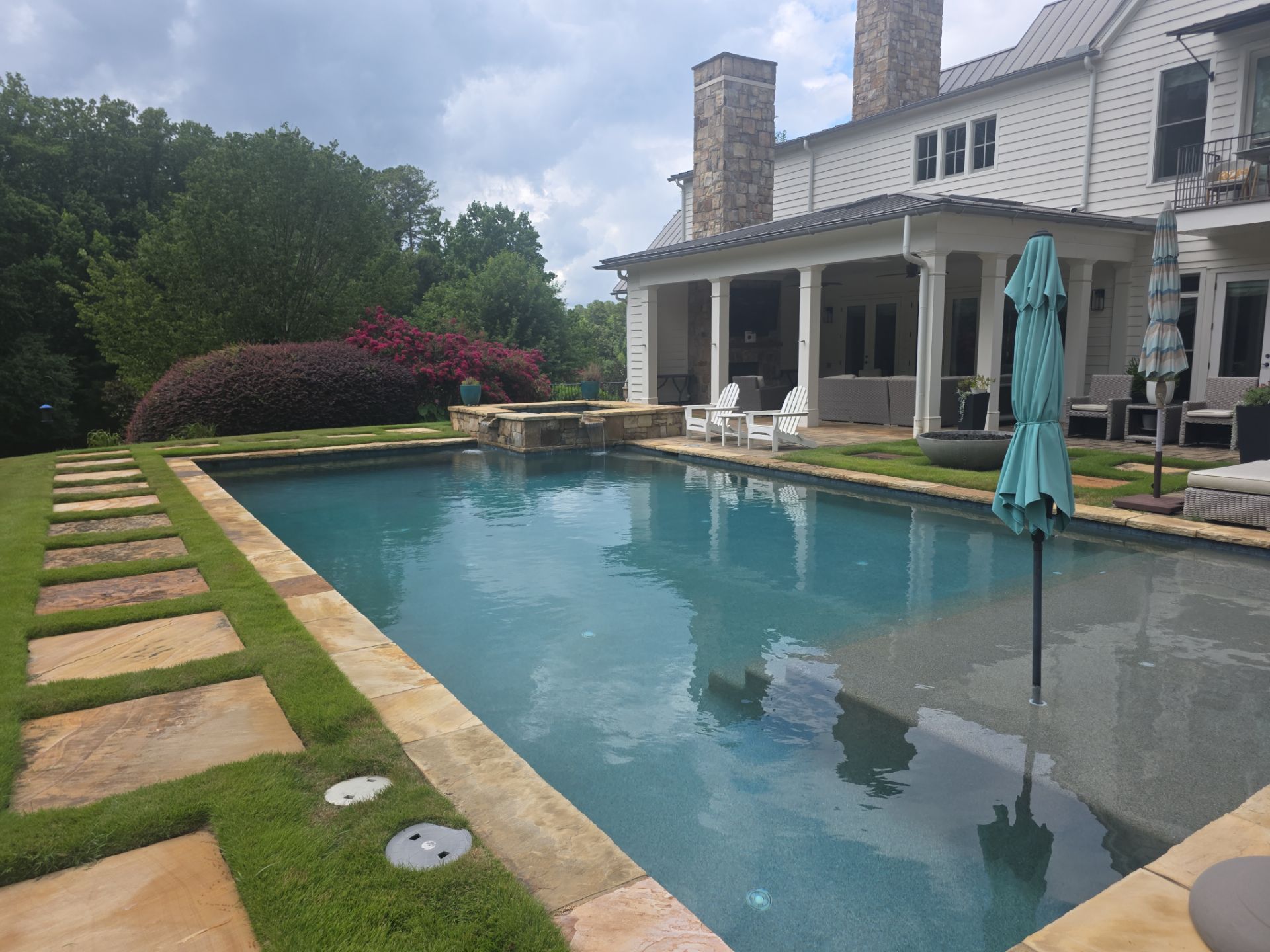 Wide-angle view of a large residential pool with stone coping and patio at a Milton, GA home after pressure washing services.
